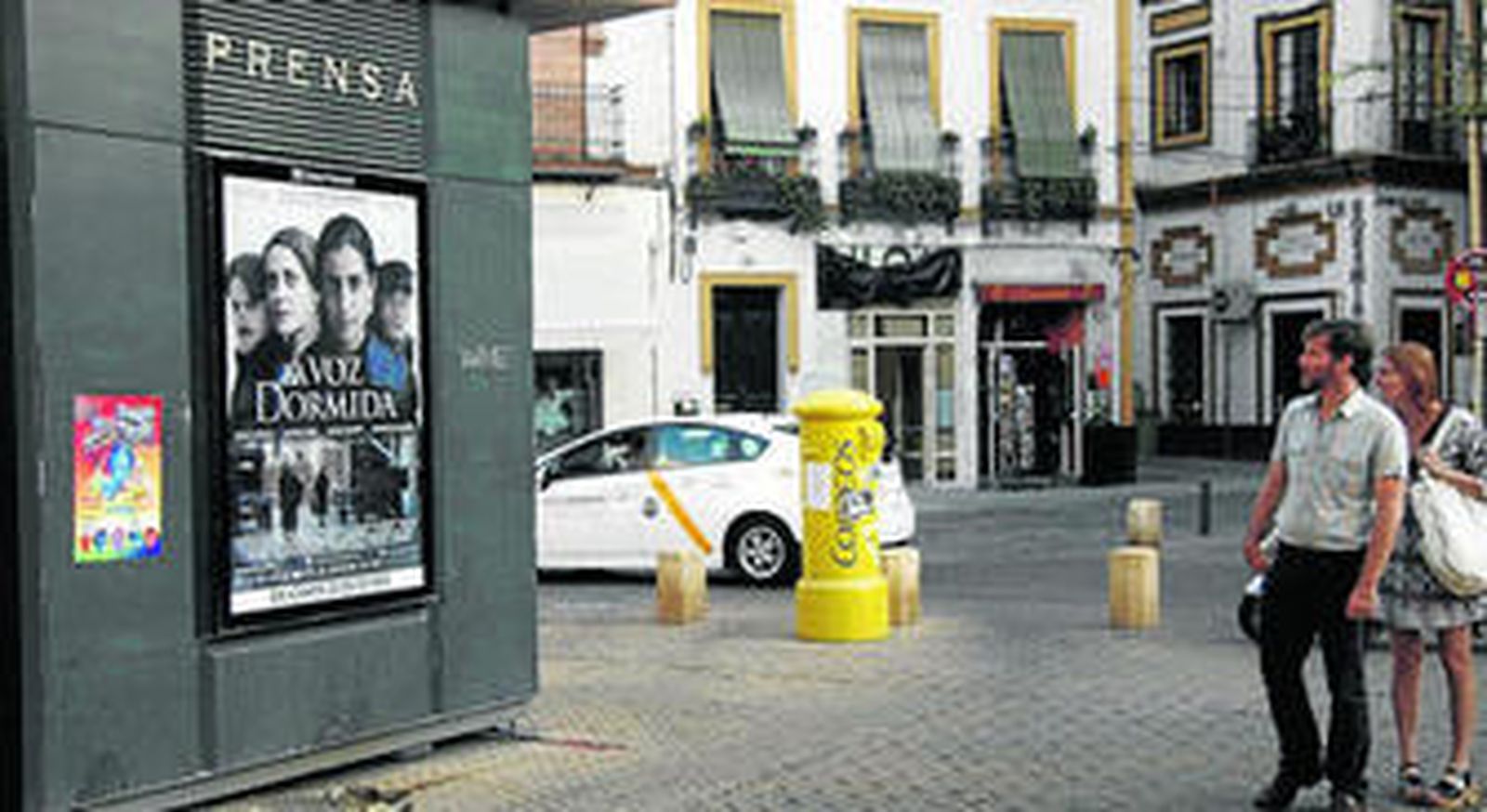 Una pareja mira el cartel de 'La voz dormida', que mañana se estrena en los cines de Sevilla.