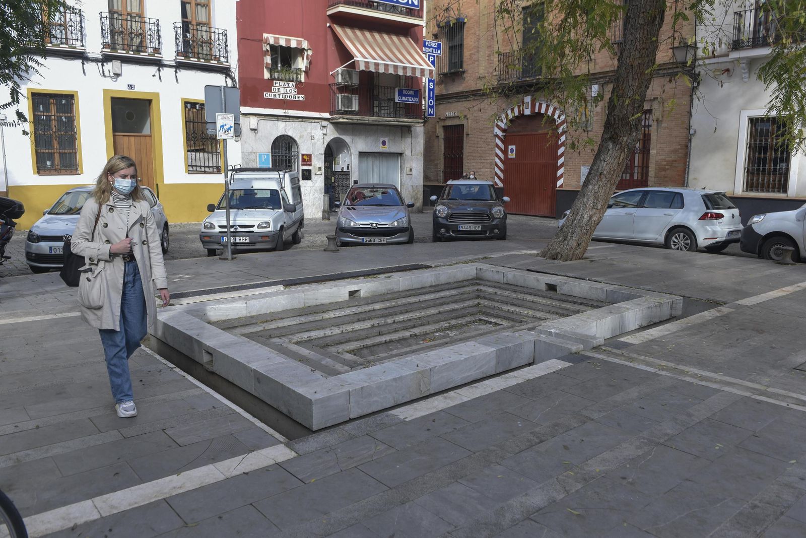 Una joven pasa ante la fuente inutilizada de la Plaza de los Curtidores.
