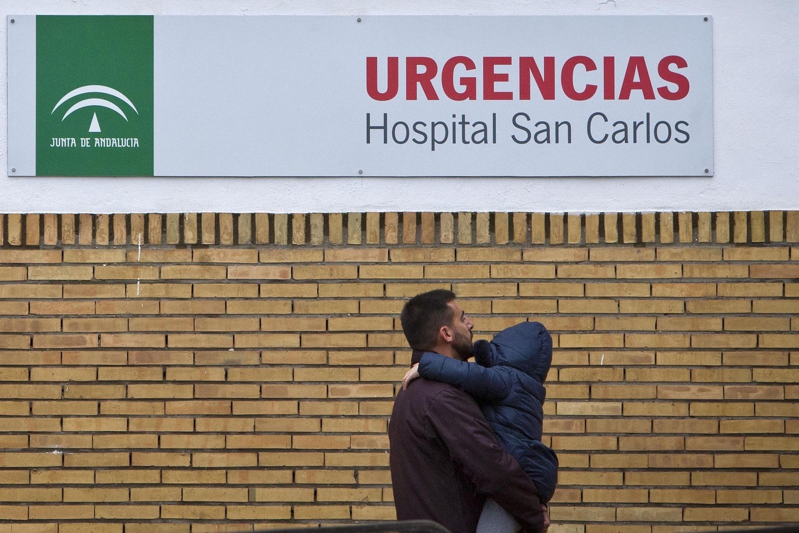 Un hombre con un niño en  brazos llega a las Urgencias del Hospital San Carlos de San Fernando.