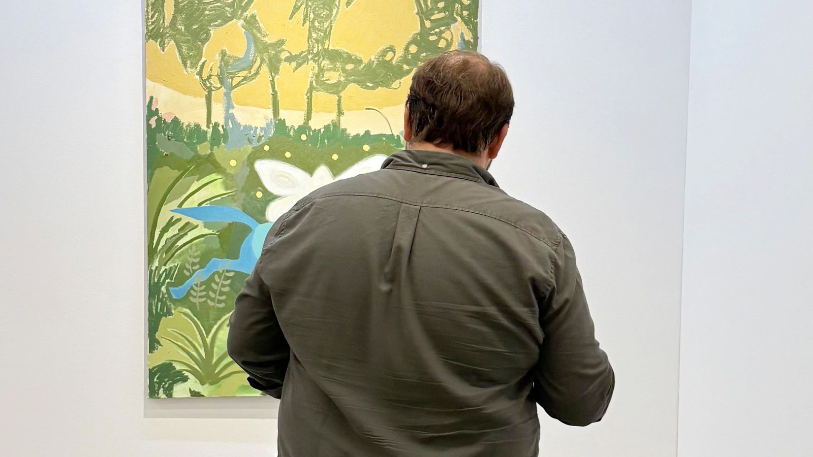 Un hombre mira un cuadro en una exposición.