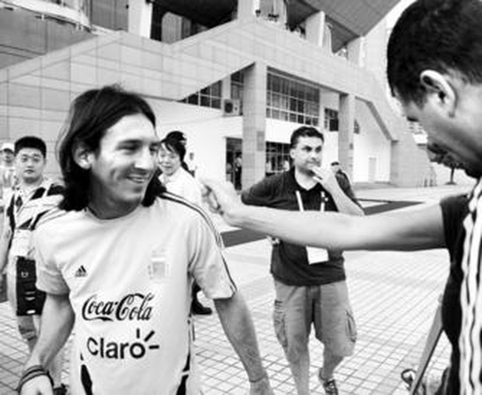 Messi, sonriente, saluda a aficionados a su llegada al entrenamiento de Argentina en Shanghai.