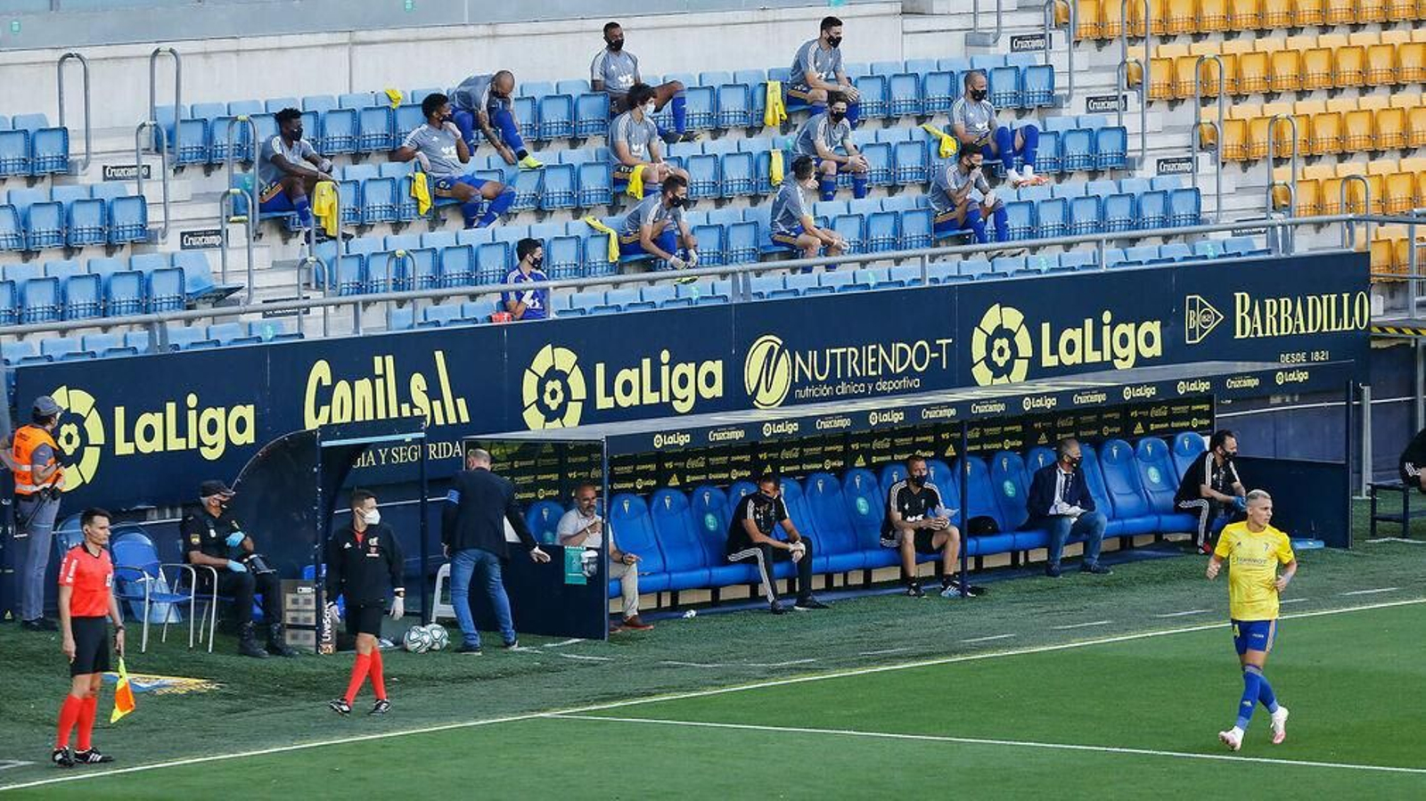 Banquillo del Cádiz y suplentes del equipo amarillo en la grada en el partido ante el Alcorcón.