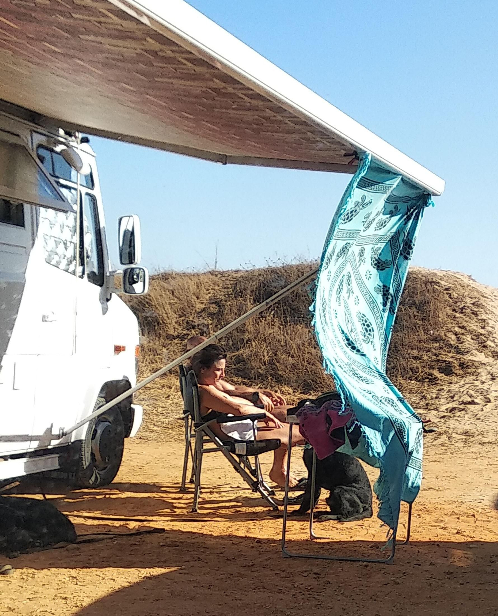 Una mujer descansa junto al lado de una autocaranava en la Costa de Huelva. Una mujer descansa junto al lado de una autocaranava en la Costa de Huelva.