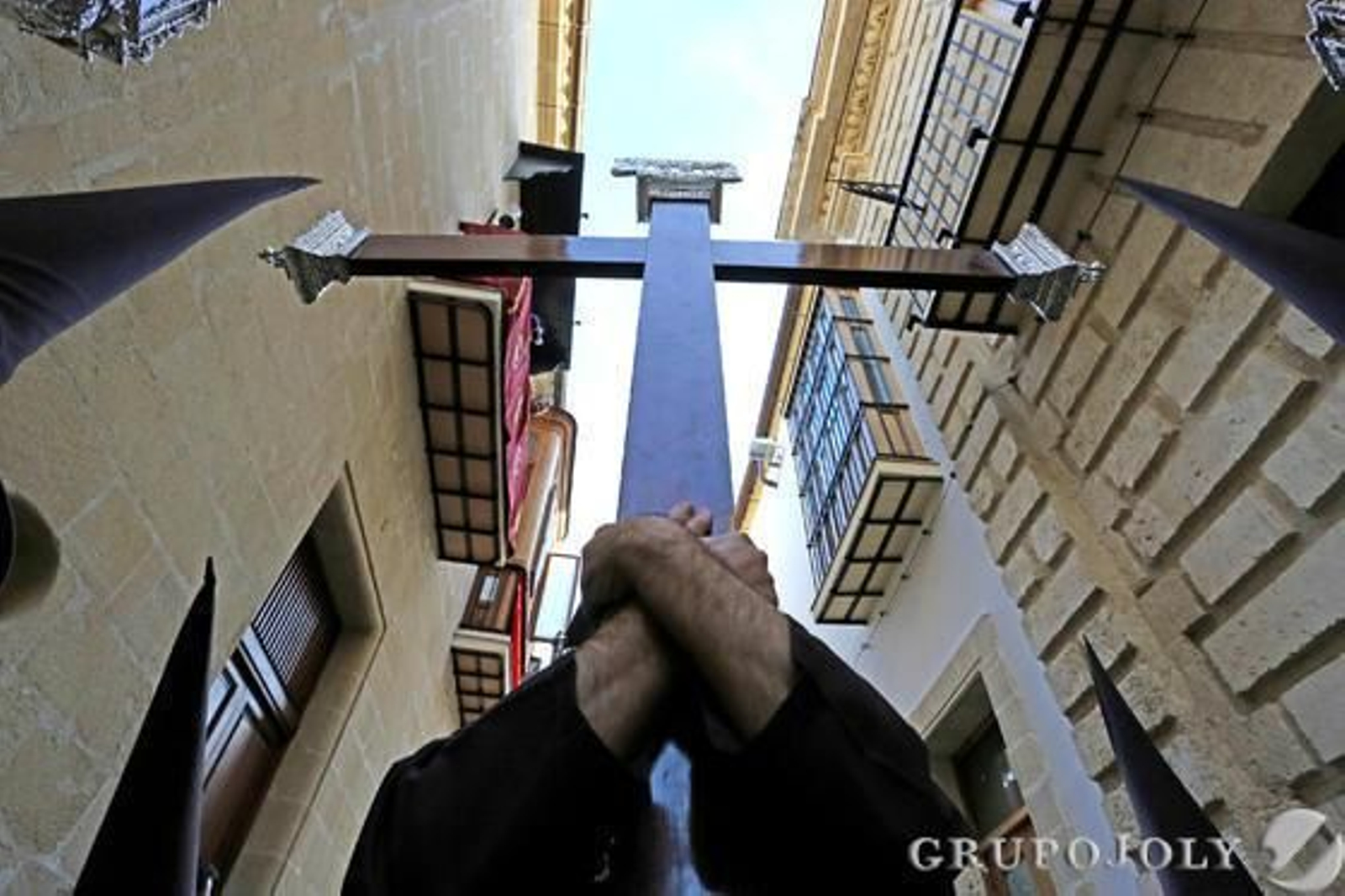 Un nazareno de la hermandad carmelita utiliza los dos brazos para llevar la cruz de guía por la ciudad.

Foto: Pascual