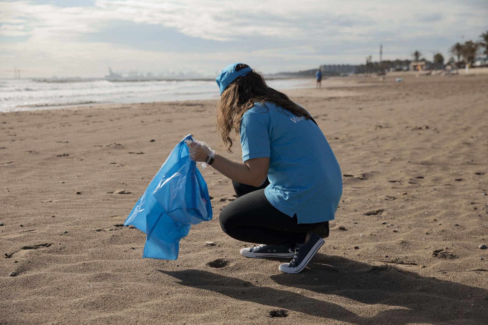 Una voluntaria de Caixabank limpia una playa.