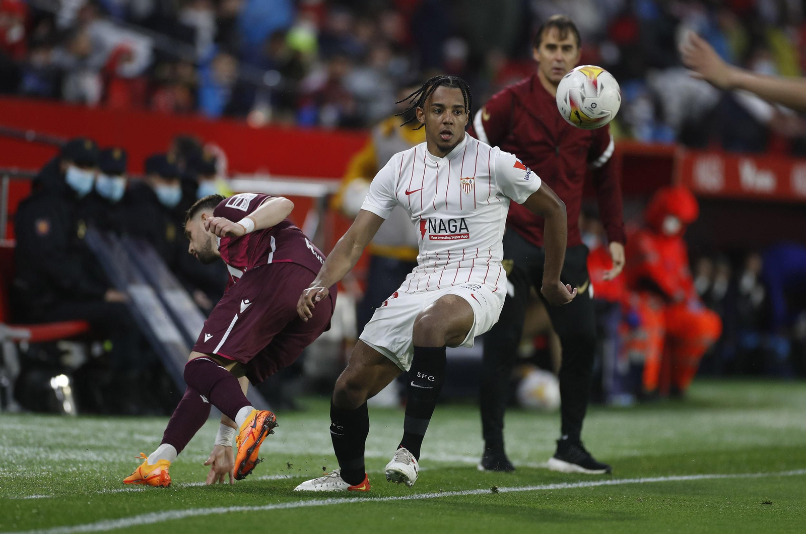 Koundé saca un balón junto a la banda con Januzaj y Lopetegui detrás.