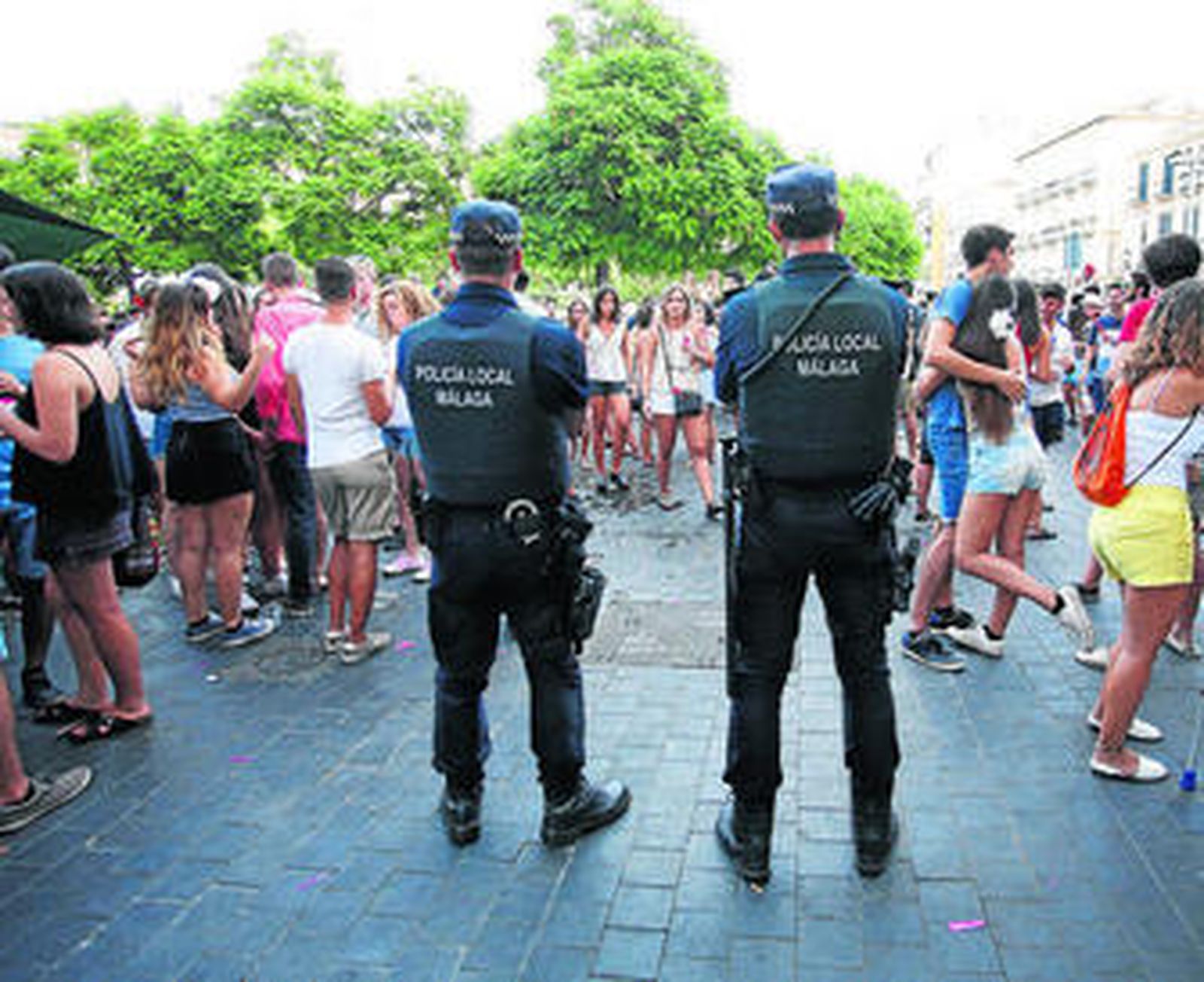 Agentes de la Policía Local observan a cientos de personas en la Plaza de la Merced.