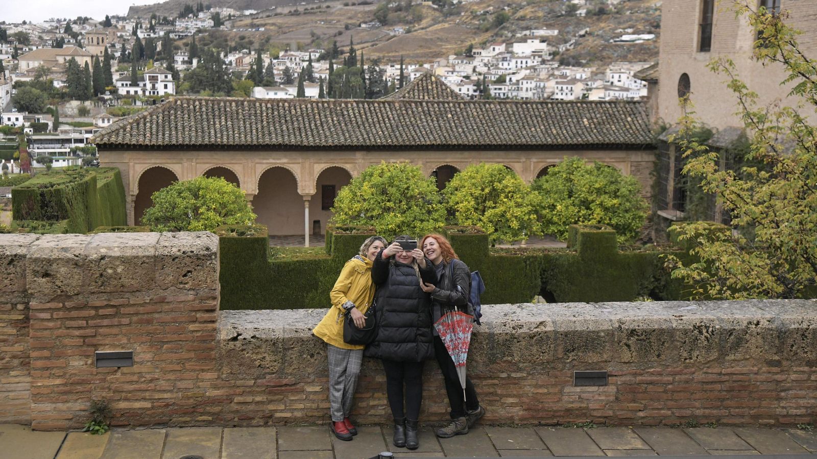 Tres mujeres se hacen un selfie en la Alhambra con vistas al Albaicín