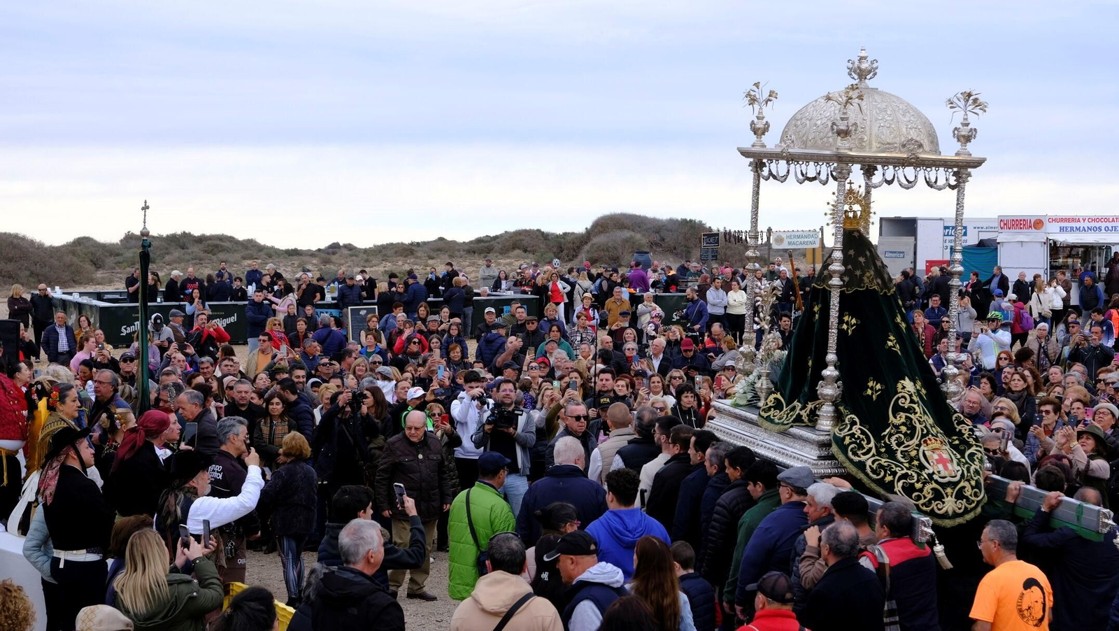 La Patrona en procesión y, al fondo, los puestos ambulantes de 2025.