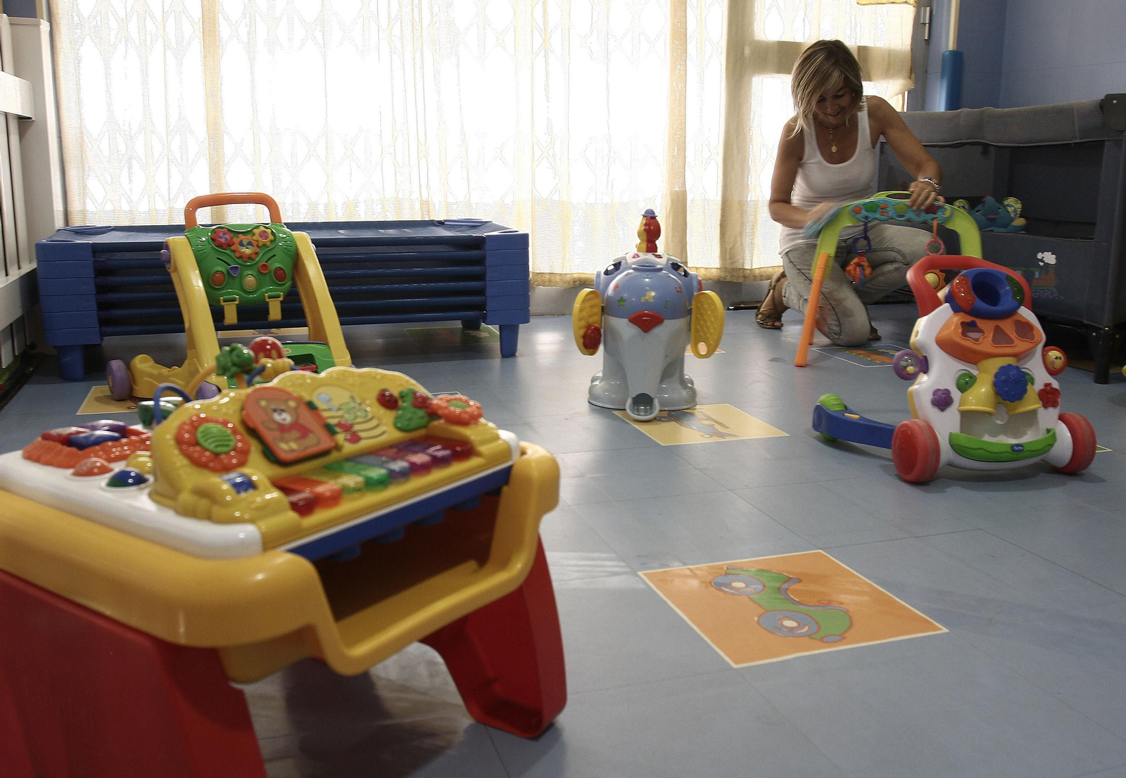 La trabajadora de una guardería prepara un aula para recibir a los alumnos.