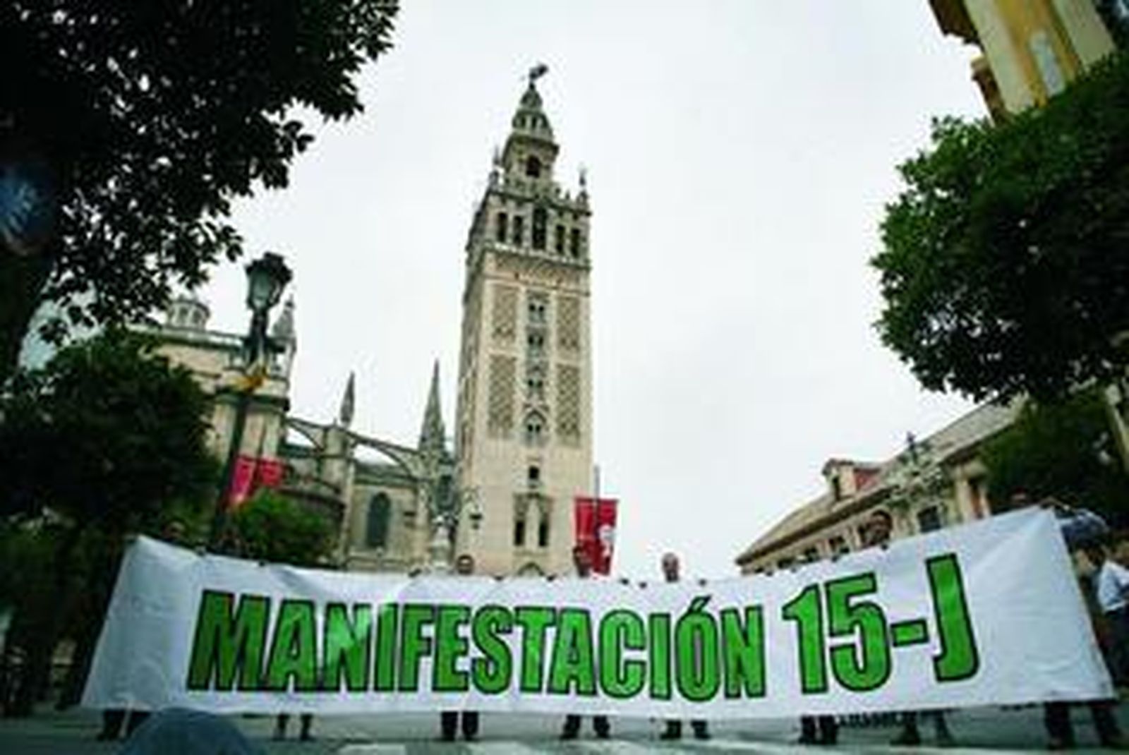 Un grupo de manifestantes posa con la pancarta del 15-J a los pies de la Giralda, ayer domingo.