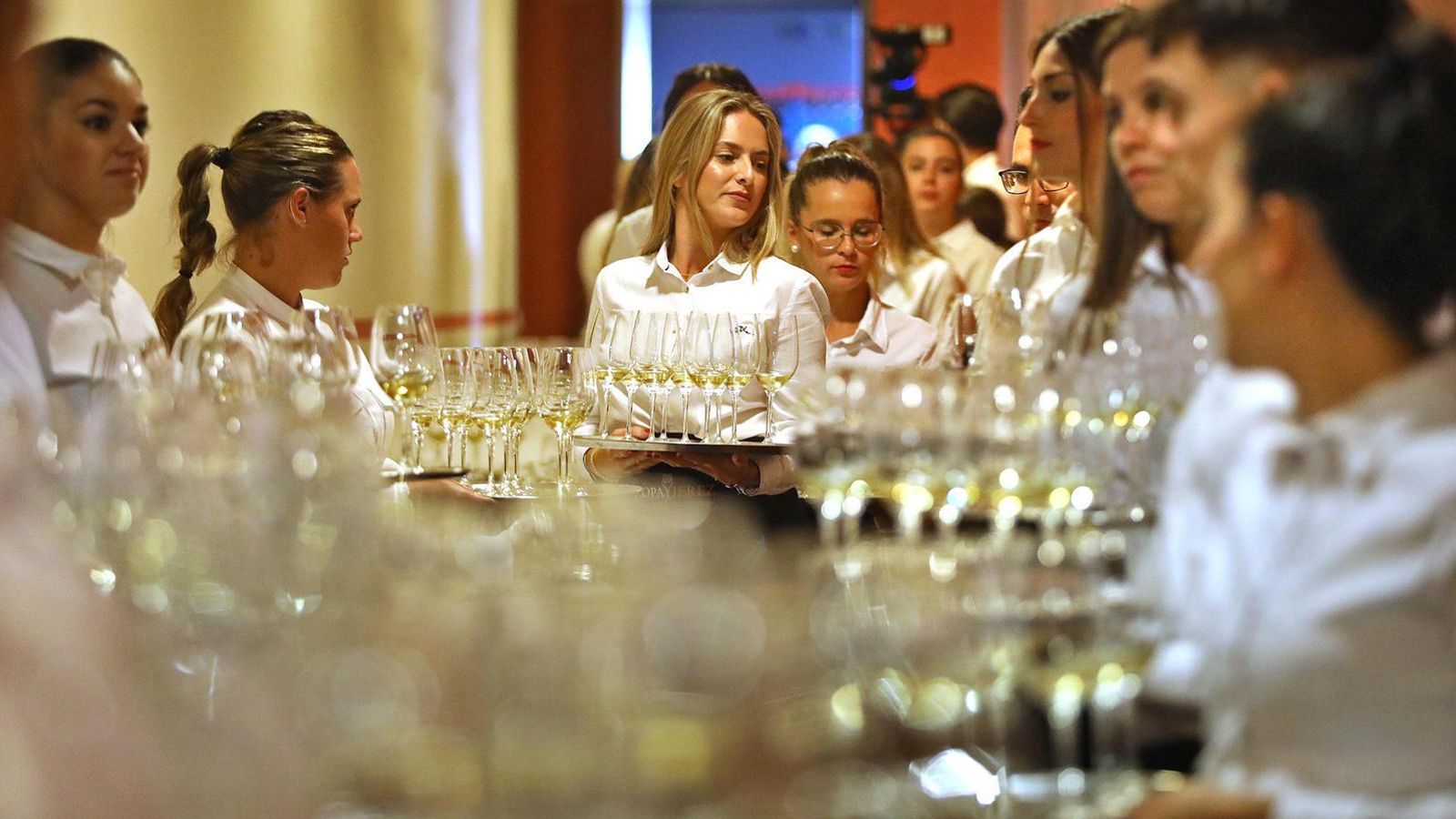Camareras con bandejas de copas de jerez dispuestas para su servicio en una cata.