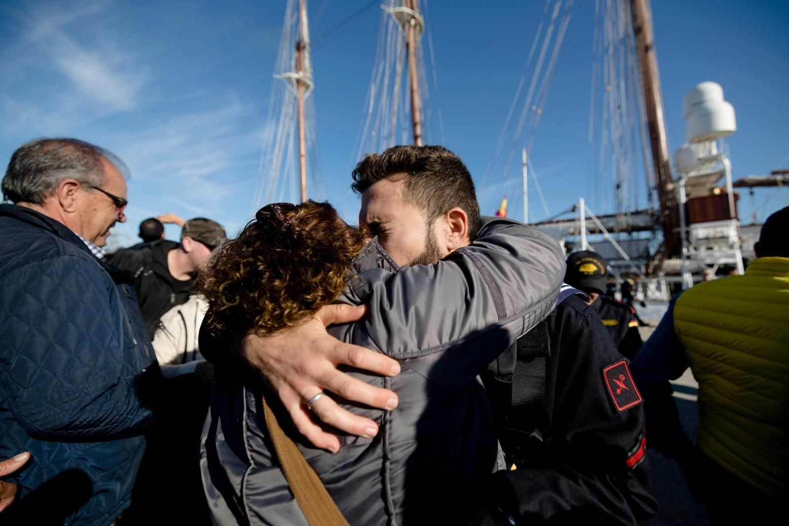 Un tripulante del Elcano se abraza a un familiar poco antes de la salida en el muelle de Cádiz.