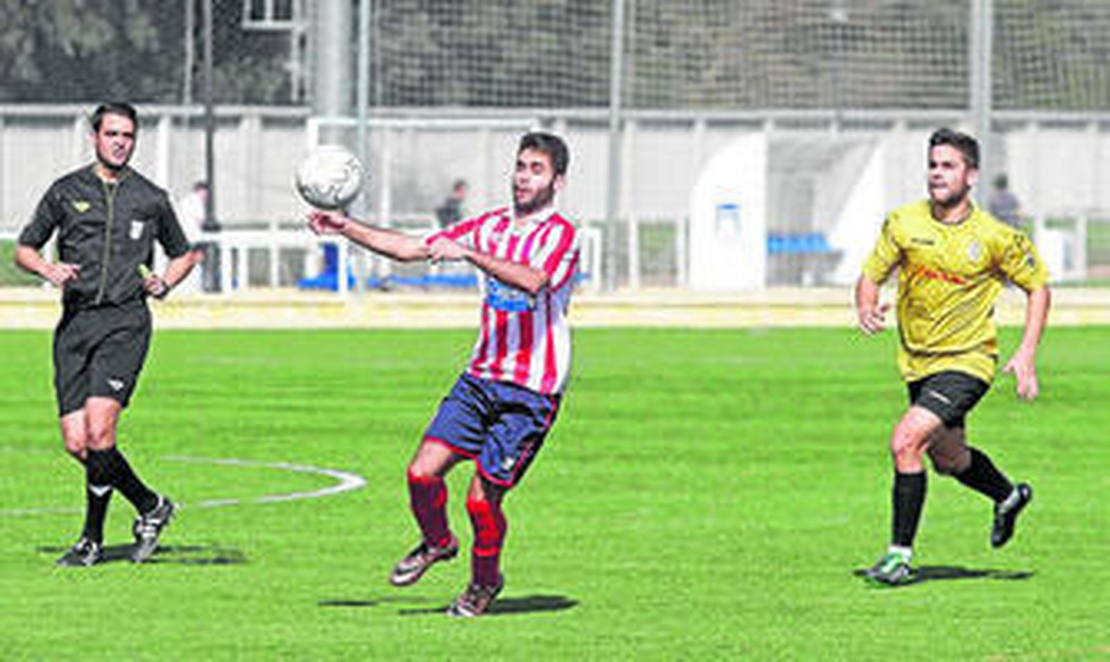 Juanca controla ante la mirada del colegiado y un rival.