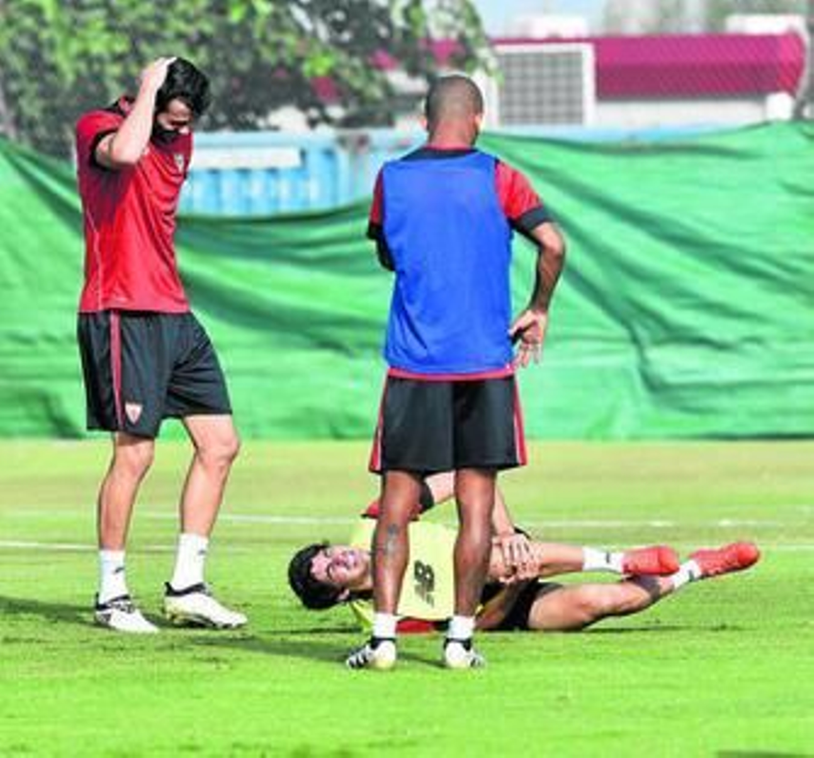 1. Carlos Fernández se duele de la rodilla izquierda en el suelo ante Iborra, que se echa la mano a la cabeza tras el chasquido que escuchó, y Mariano.  2. Jugadores y técnicos se interesan por el jugador mientras es atendido. 3. El delantero necesitó ayuda para abandonar el campo.