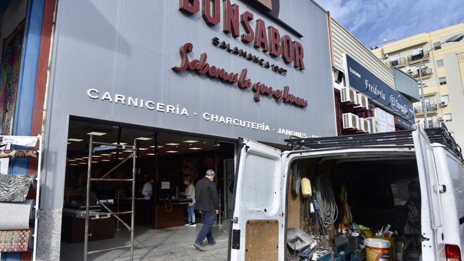 La entrada a la tienda asaltada, con la furgoneta de los trabajadores que reparan en la puerta en primer plano.