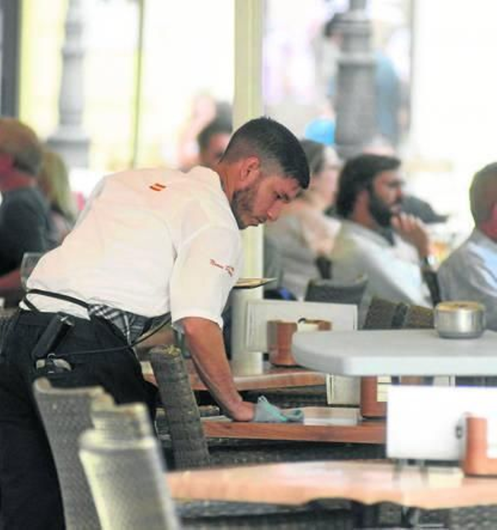 Un camarero limpia y  recoge una mesa en Córdoba.