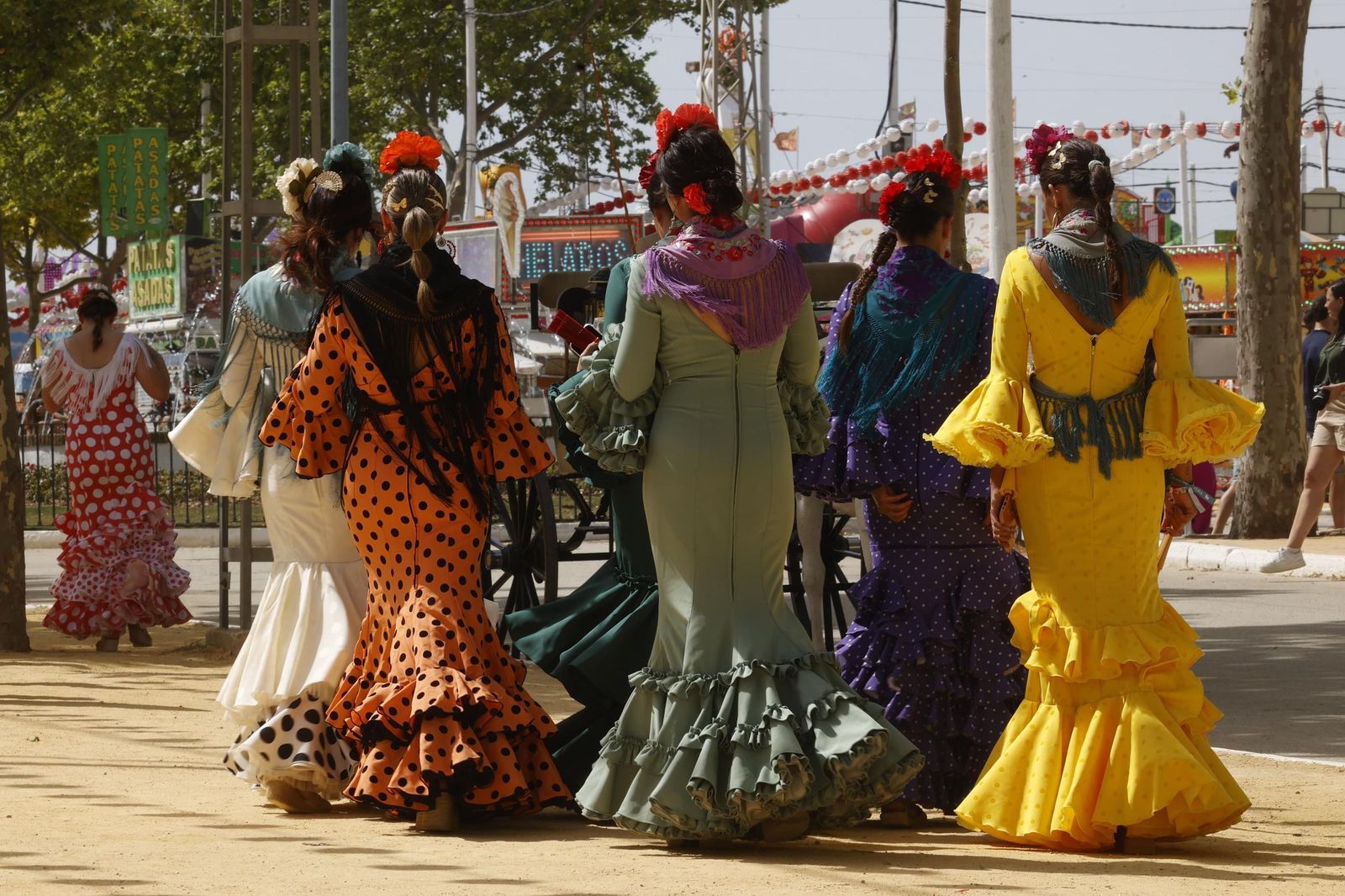 Mujeres vestidas de flamenca paseando por el recinto de Las Banderas.