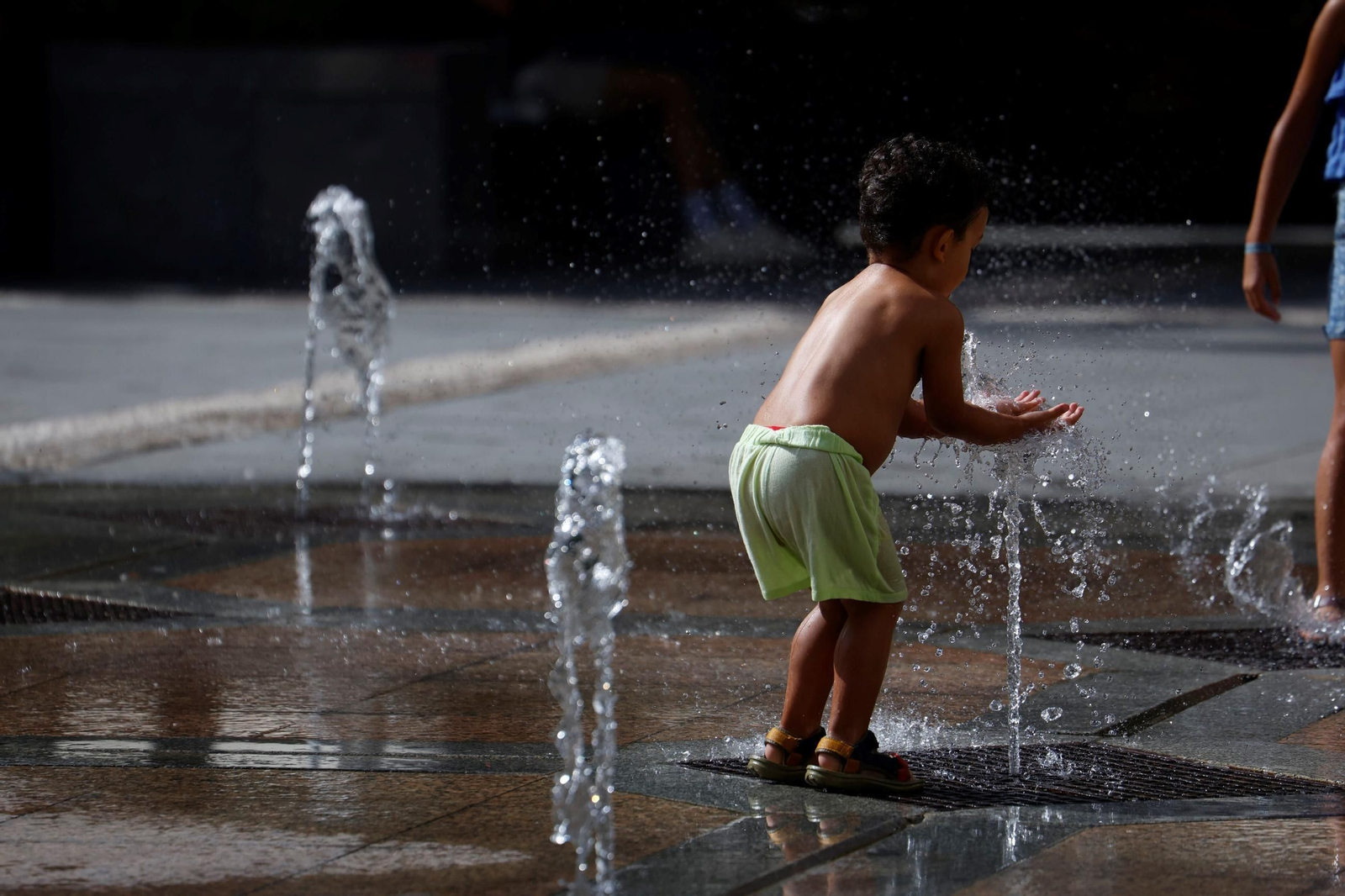 Un niño se refresca en una fuente en Córdoba.