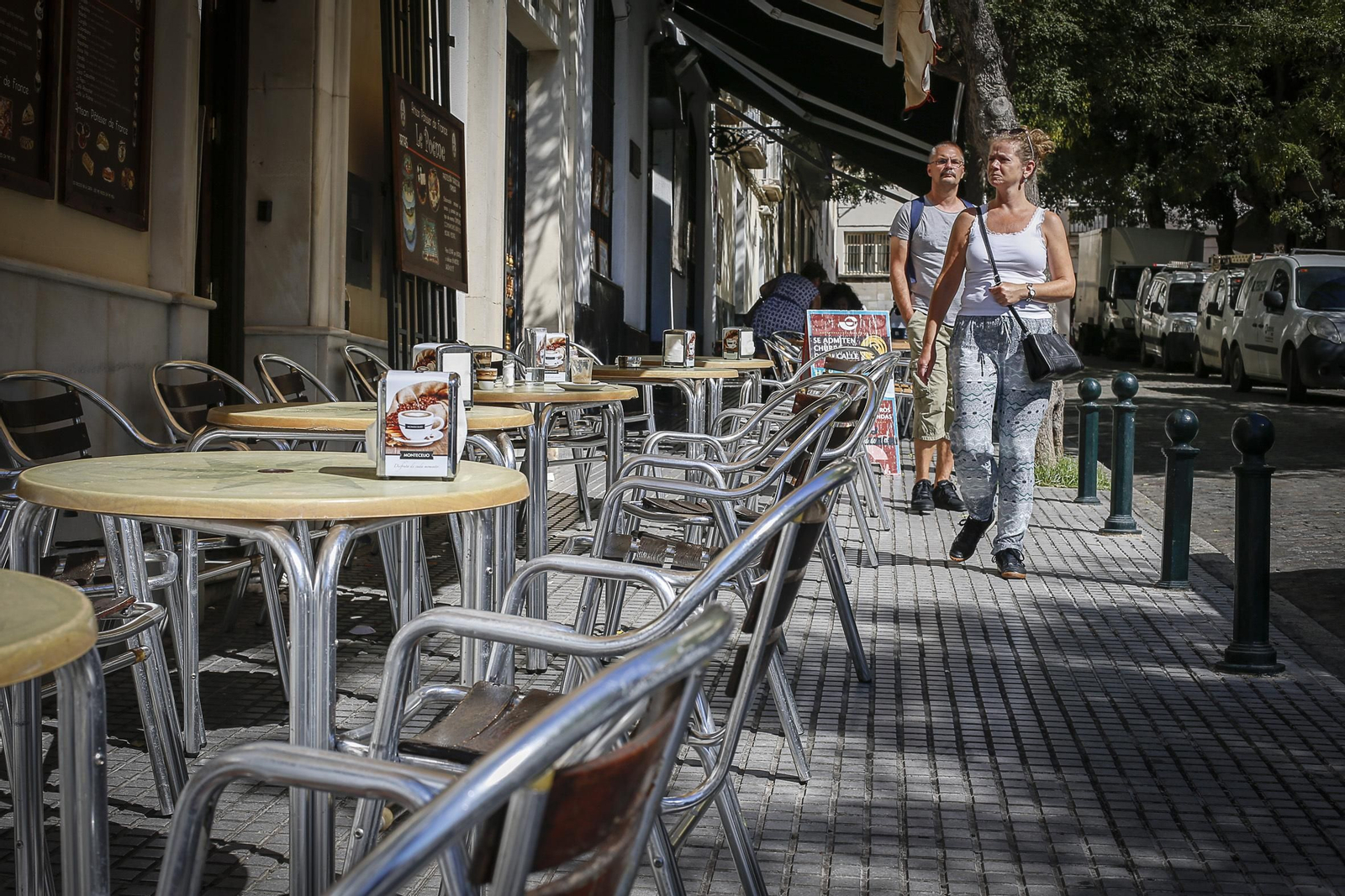 Dos turistas pasando ayer junto a la terraza vacía de una cafetería en el centro de Cádiz.