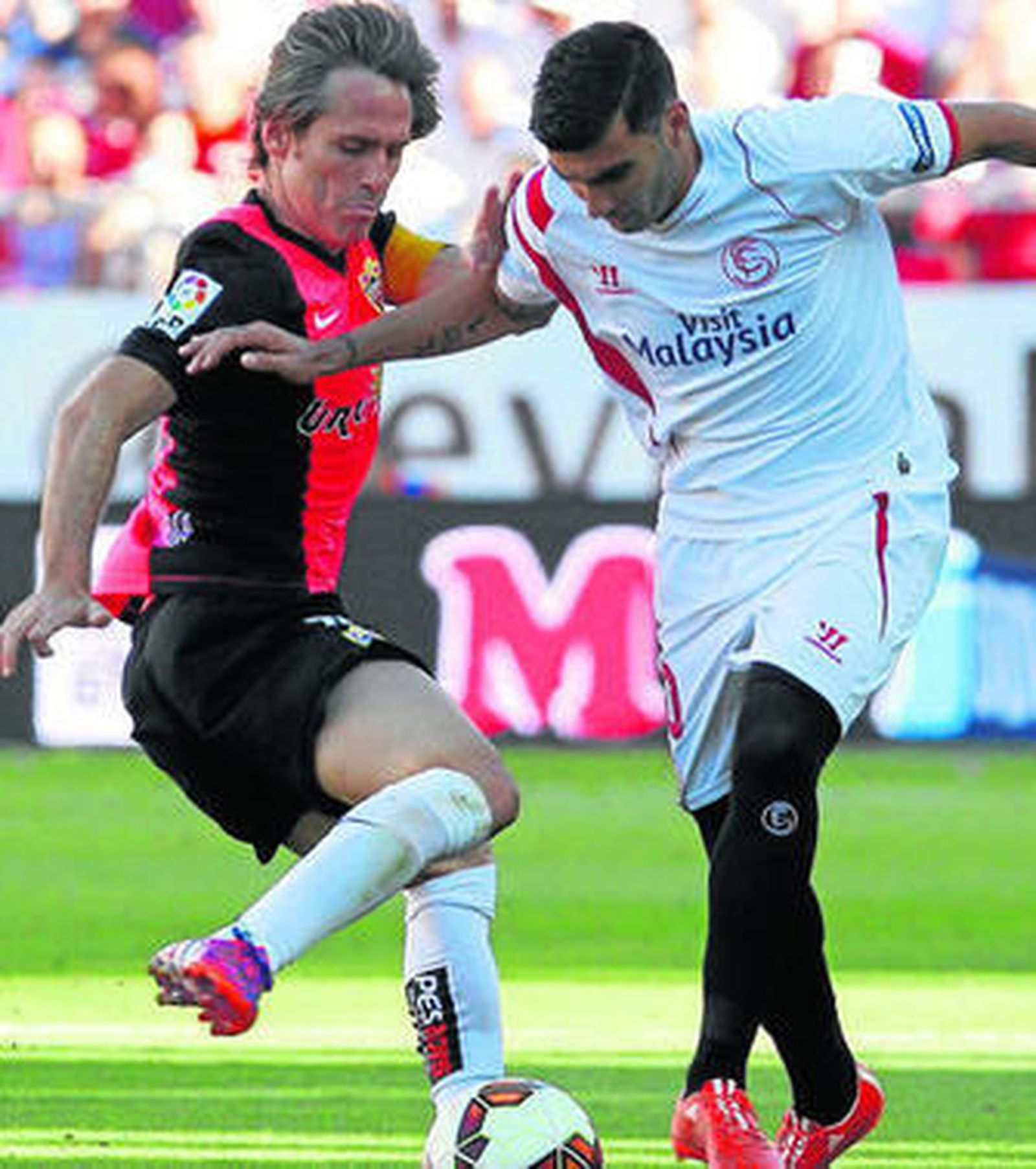 Corona, capitán rojiblanco ayer en Sevilla, intenta robarle el esférico al sevillista Reyes.