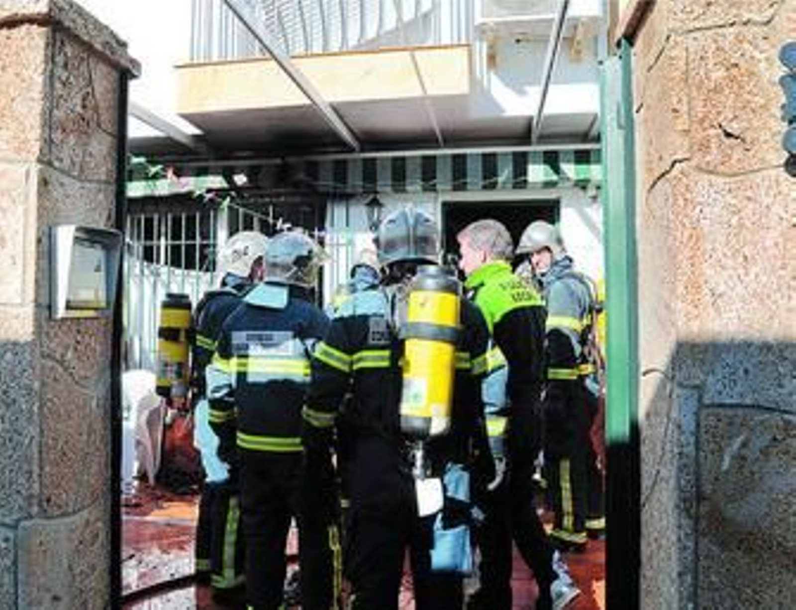 Bomberos y policías locales, ante la casa incendiada ayer en Guadalcacín.