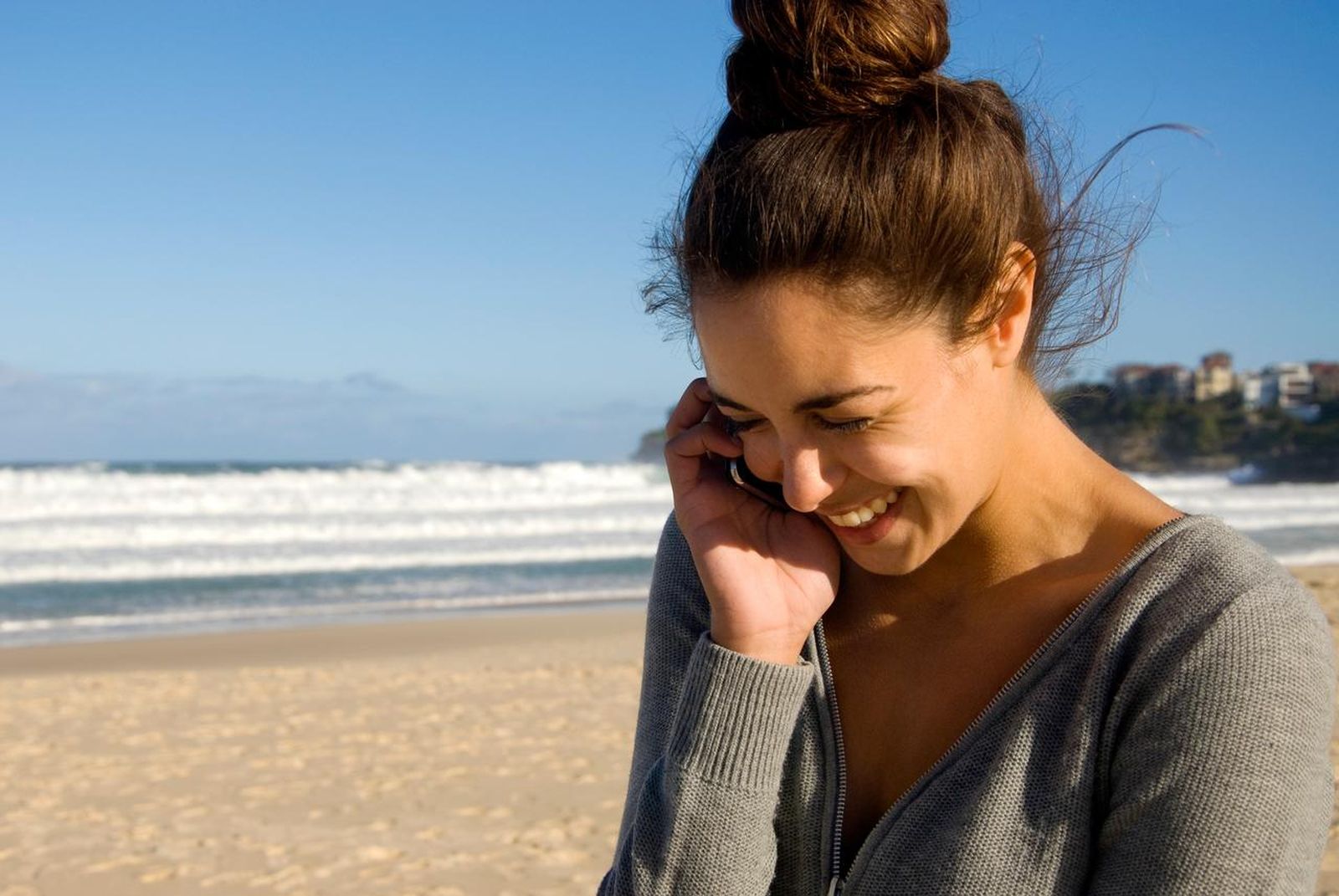 Mujer hablando por teléfono en la playa.