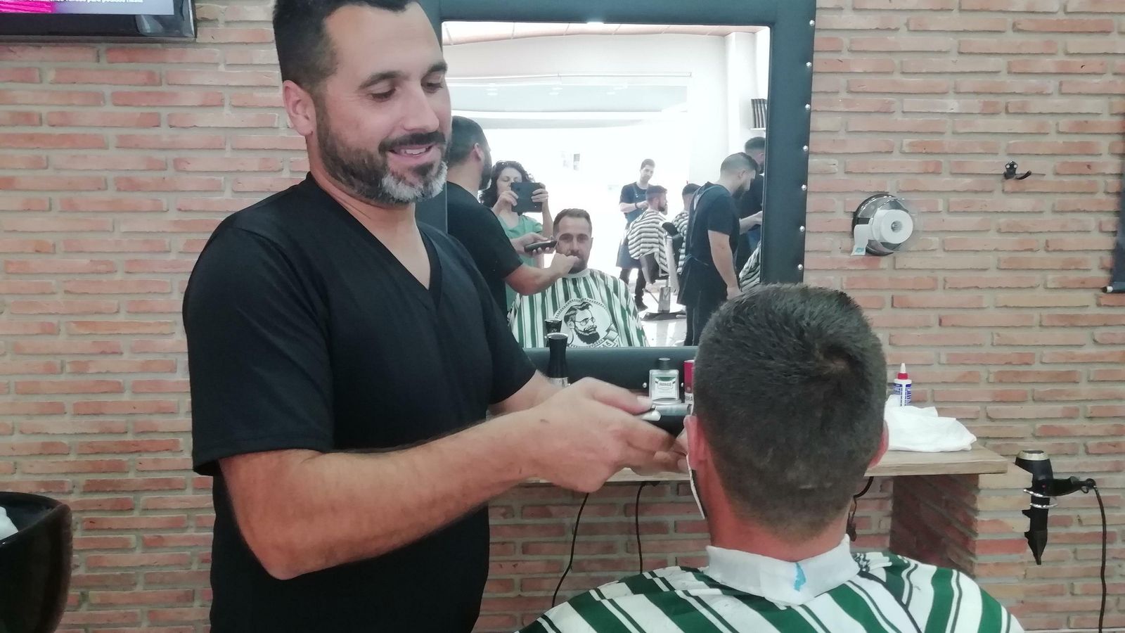 Juan García, en su peluquería Nani, con un cliente.