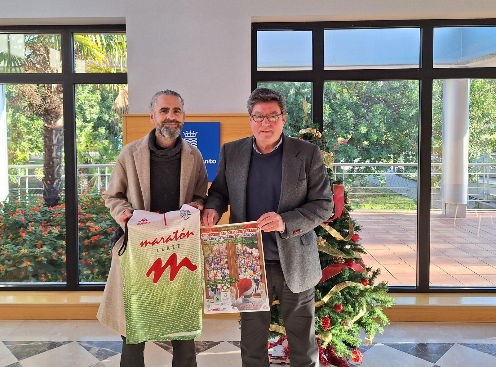 Francis Benítez y José Ángel Aparicio posan con el cartel de la prueba solidaria.