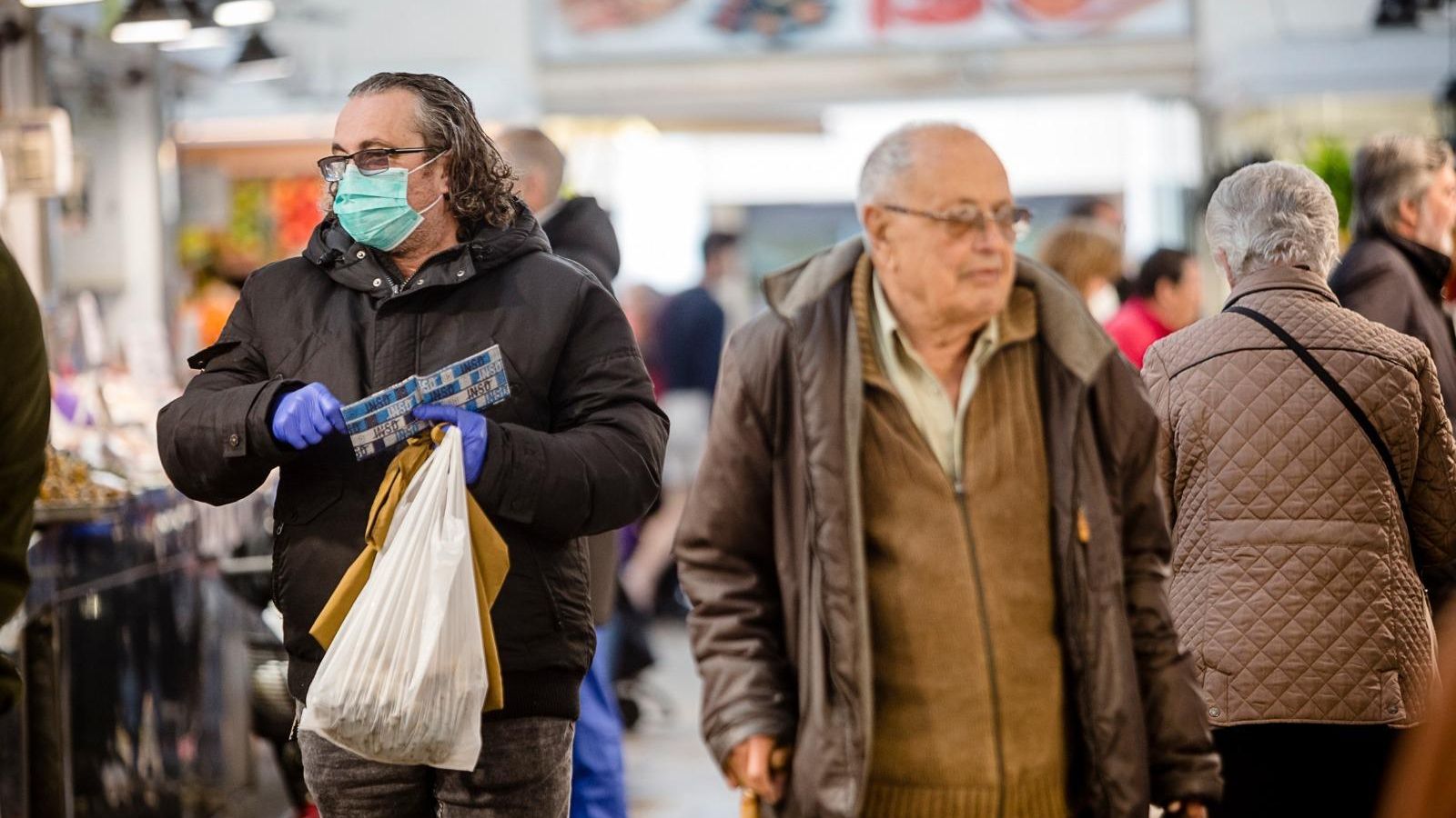Un hombre compra con mascarillas y guantes.