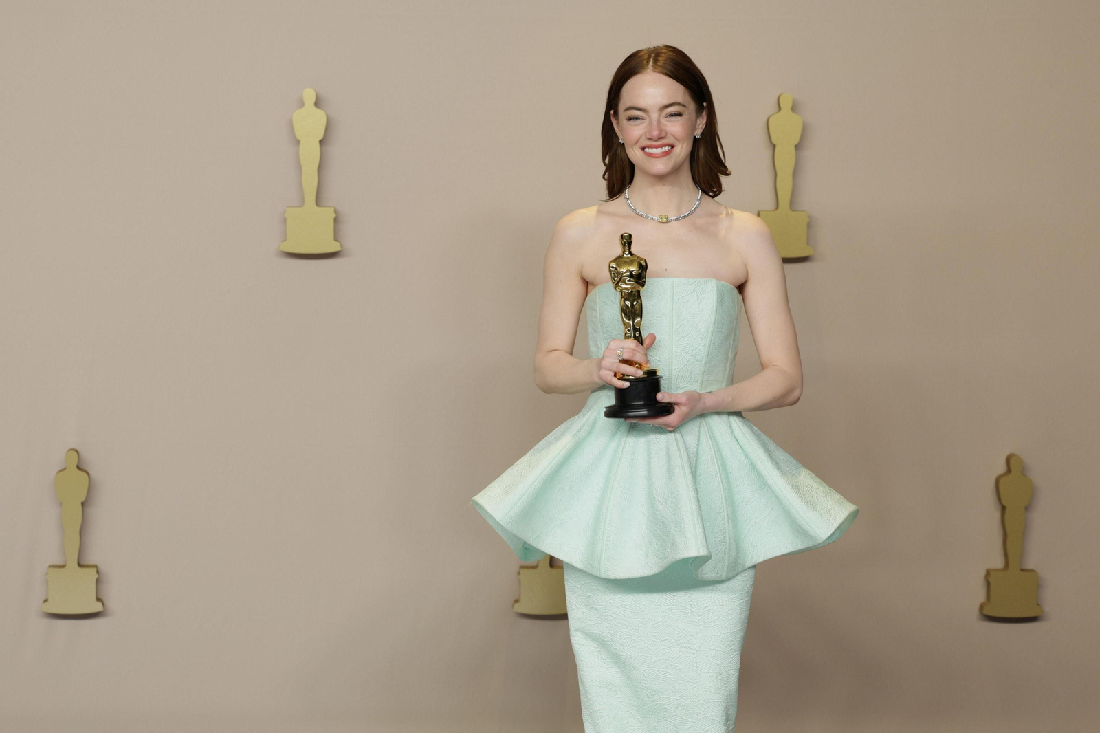 La premiada Emma Stone, con un favorecedor vestido verde menta, plisado en una falda superior, de Louis Vuitton, con el pelo suelto