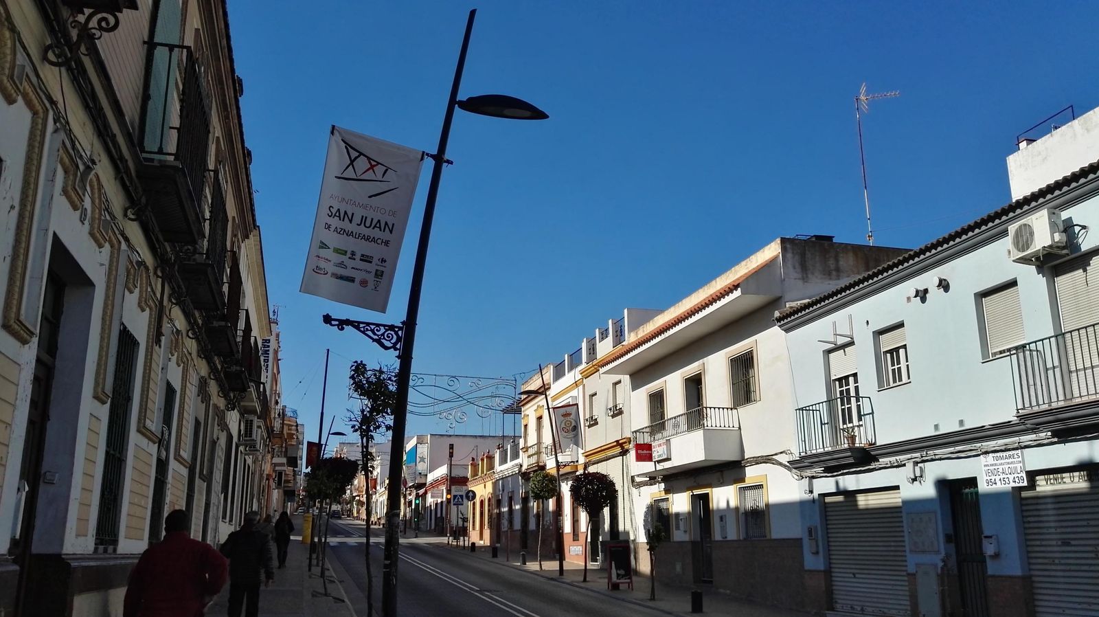 Una vista de una calle de San Juan con farolas y el alumbrado navideño ya colocado.