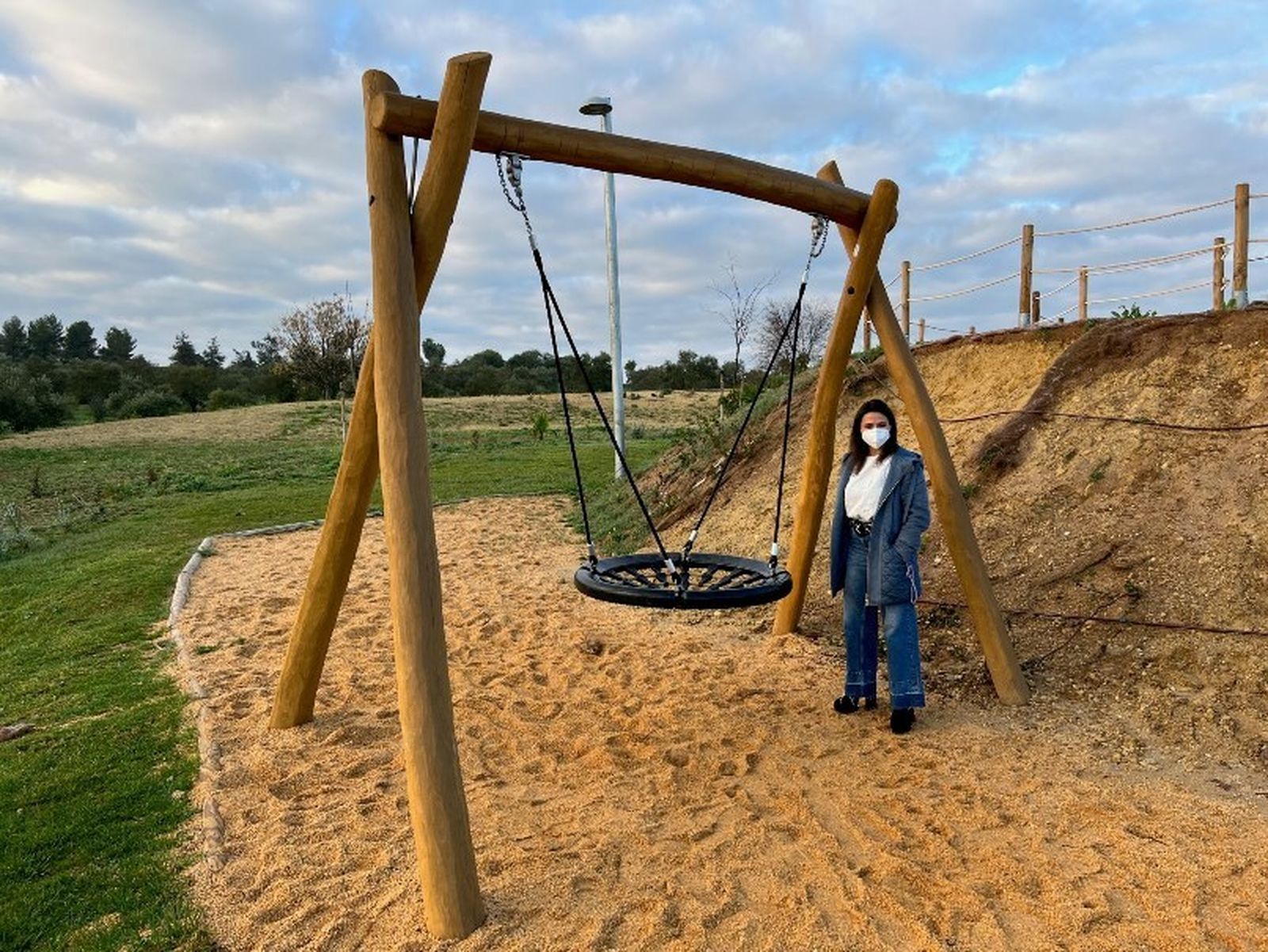 La concejala de Medio Ambiente y Sostenibilidad Urbana del Ayuntamiento de Tomares, Cristina Jiménez, junto a un juego inclusivo en el Parque Alto Aljarafe de Tomares.