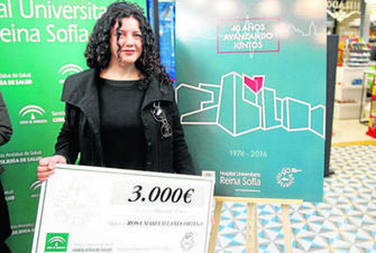 Rosa María Illanes posa delante de la obra con la que ha ganado el concurso y el premio recibido.