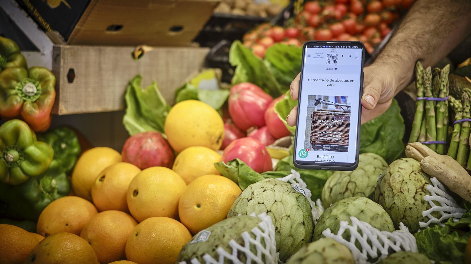Un vendedor de frutas del Mercado Central muestra en su teléfono móvil la web de la venta online.