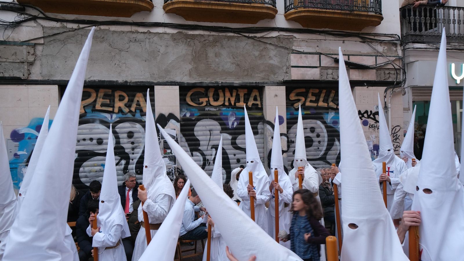 Nazarenos del Dulce Nombre pasan junto al establecimiento cerrado del que pendía la placa retirada por los bomberos.