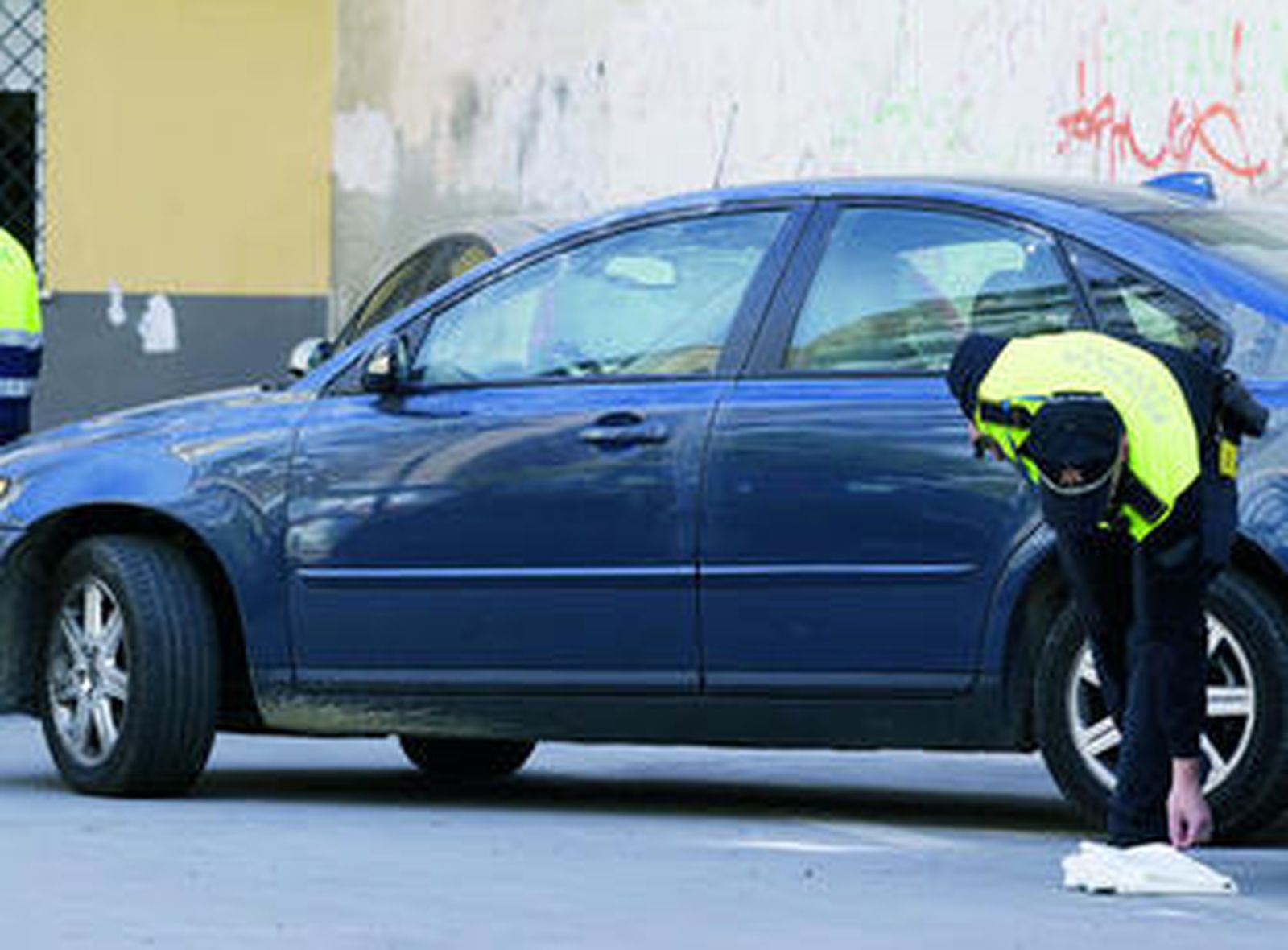 Un agente de la Policía Local de Málaga junto al coche en cuyo maletero apareció el cadáver.