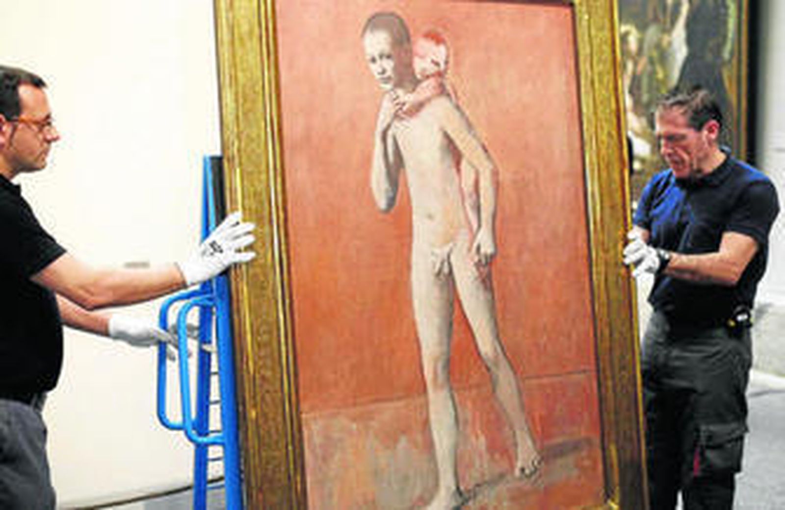 Operarios manejando el óleo 'Los dos hermanos', antes de colgarlo.