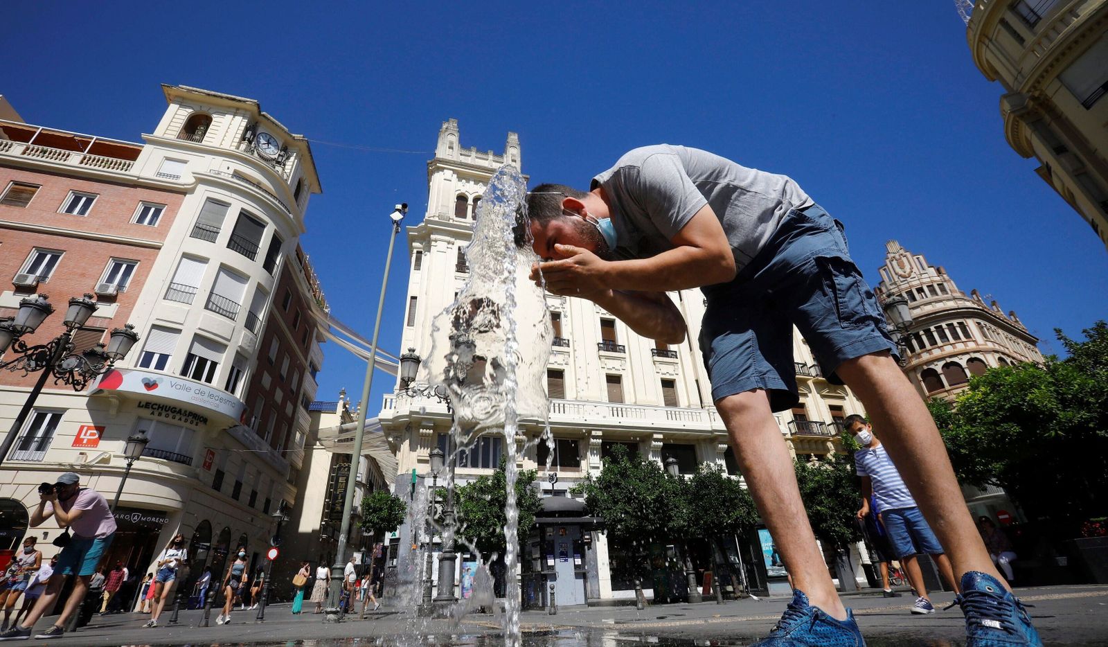 Un hombre se refresca en los chorros de la plaza de las Tendillas.