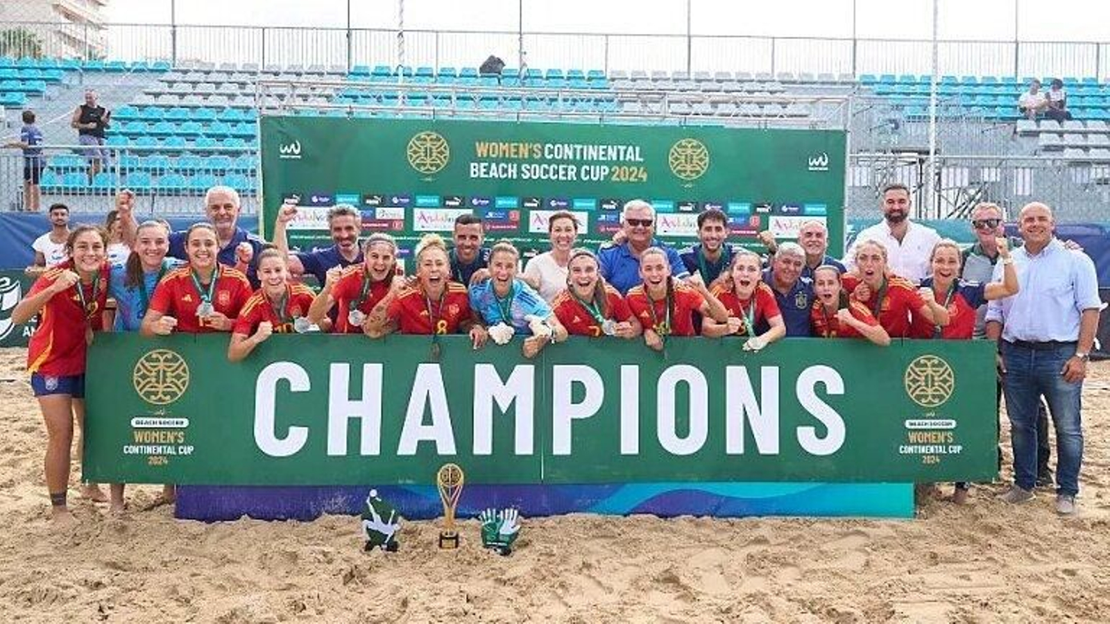 Las jugadoras de la selección española y su cuerpo técnico posan sobre la arena con el título conquistado en Cádiz.