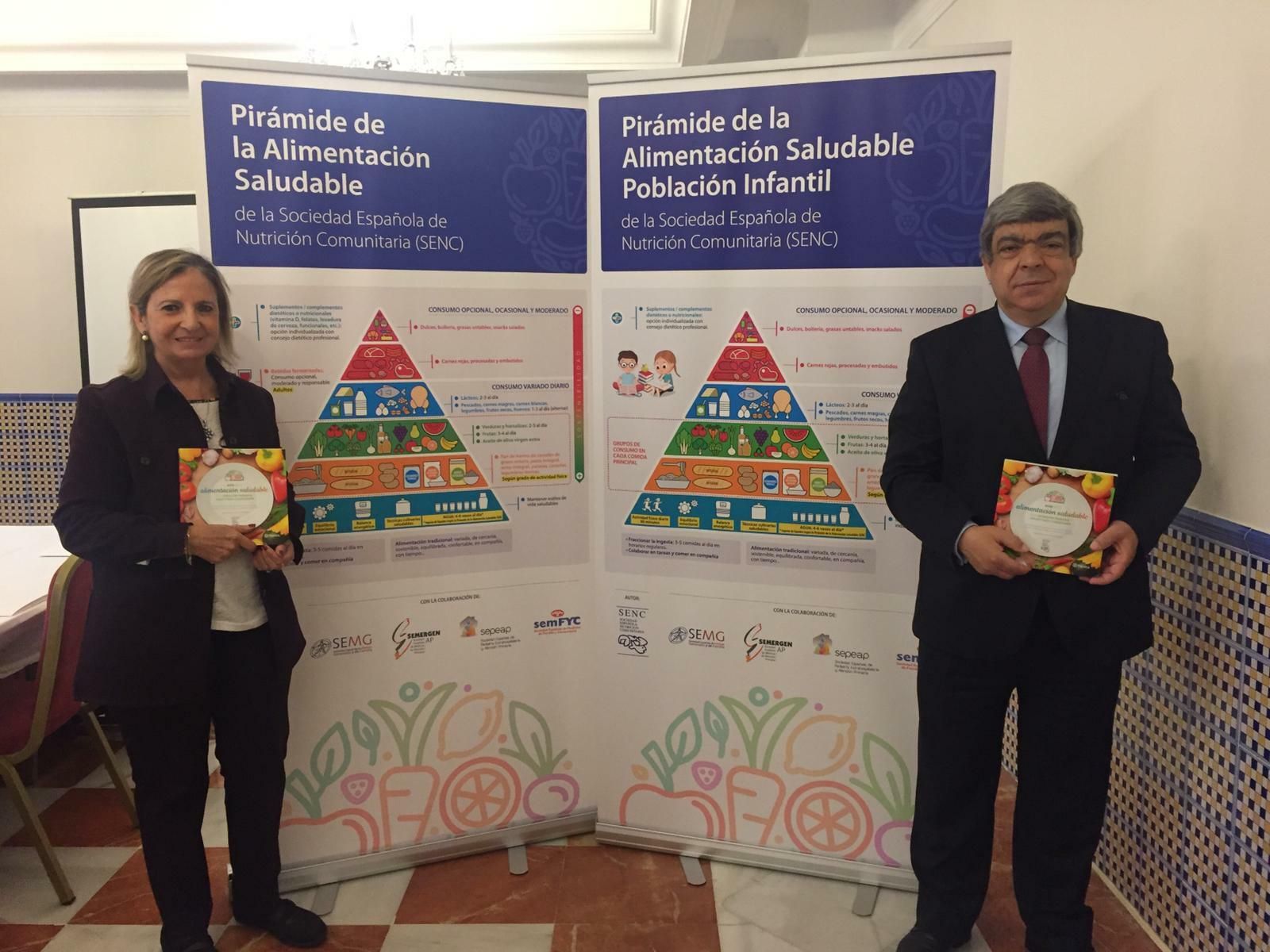 Amelia Rodríguez y Javier Aranceta posan con la Guía junto a la nueva Pirámide de la Alimentación Saludable.