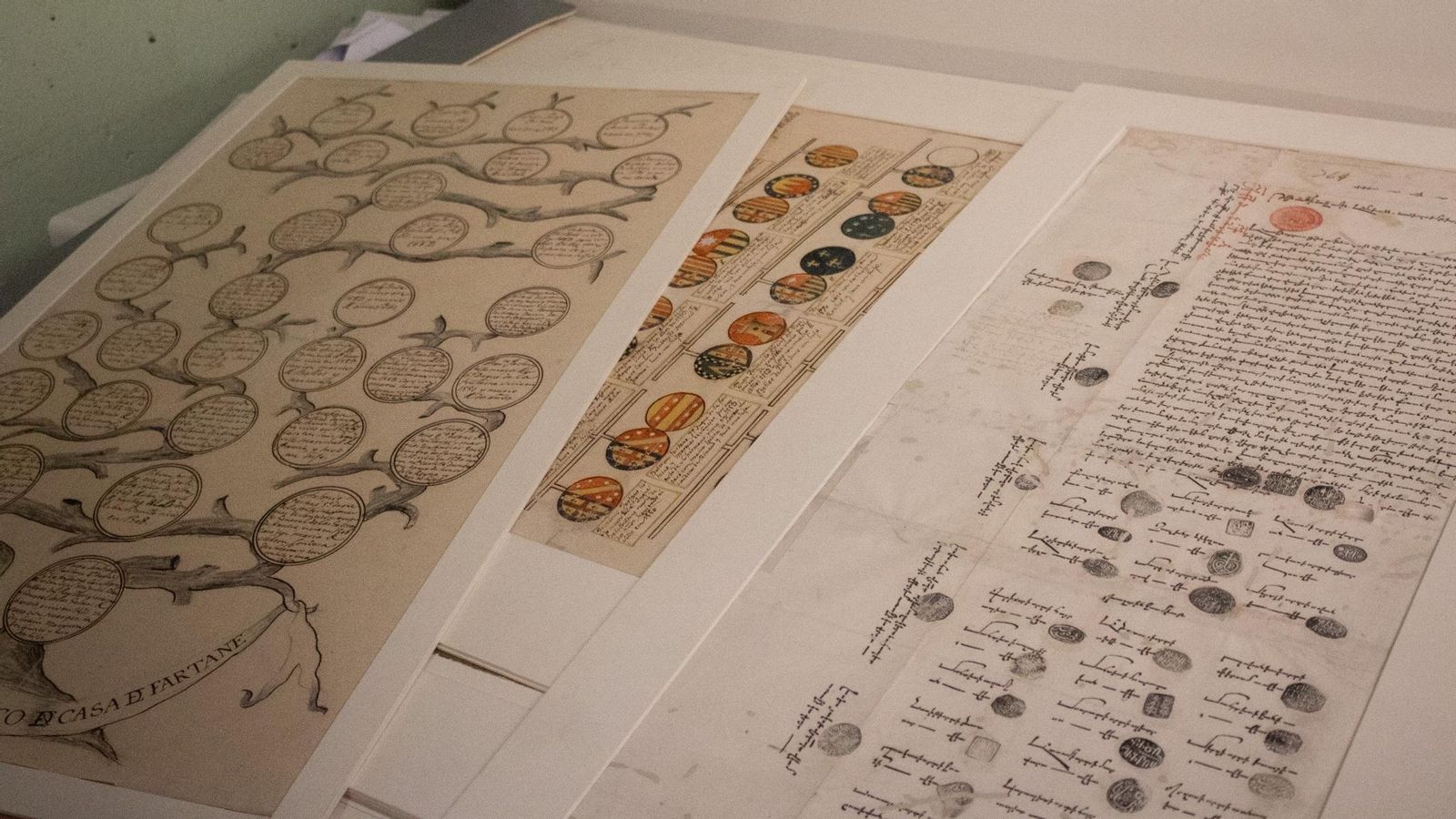 Una carta de pagos escrita en armenio junto a distintos pliegos de árboles genealógicos.