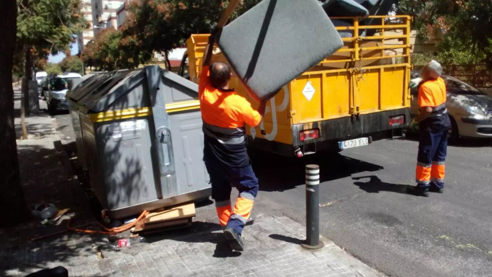 Dos operarios del servicio de limpieza de Lipasam arrojan un mueble al camión