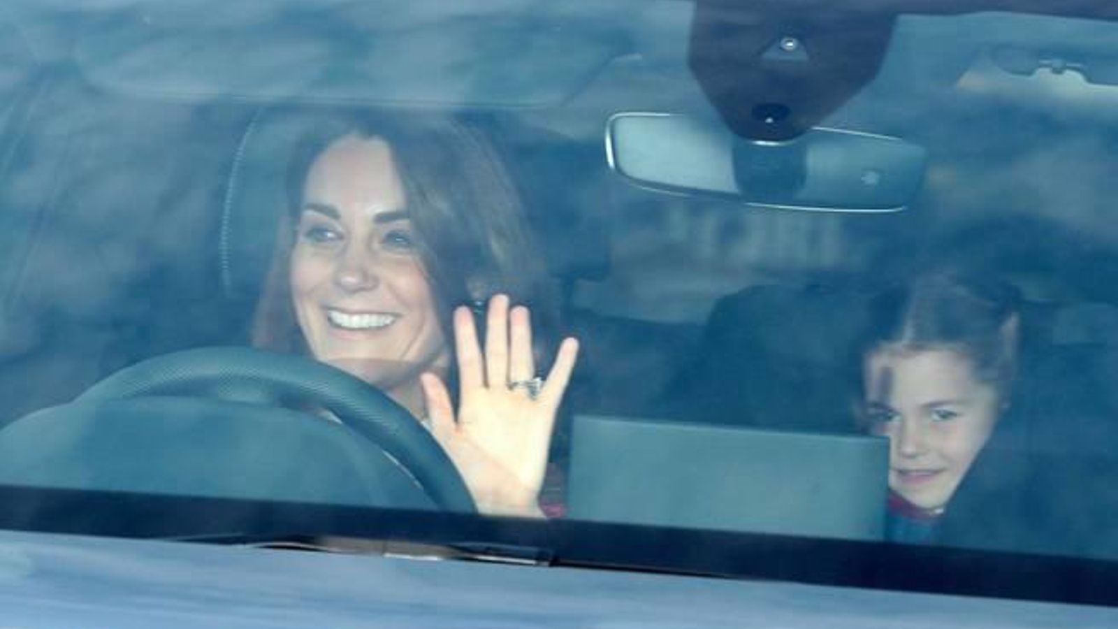 La duquesa de Cambridge saluda a los curiosos, con su hija, Carlota, en el asiento de detrás.