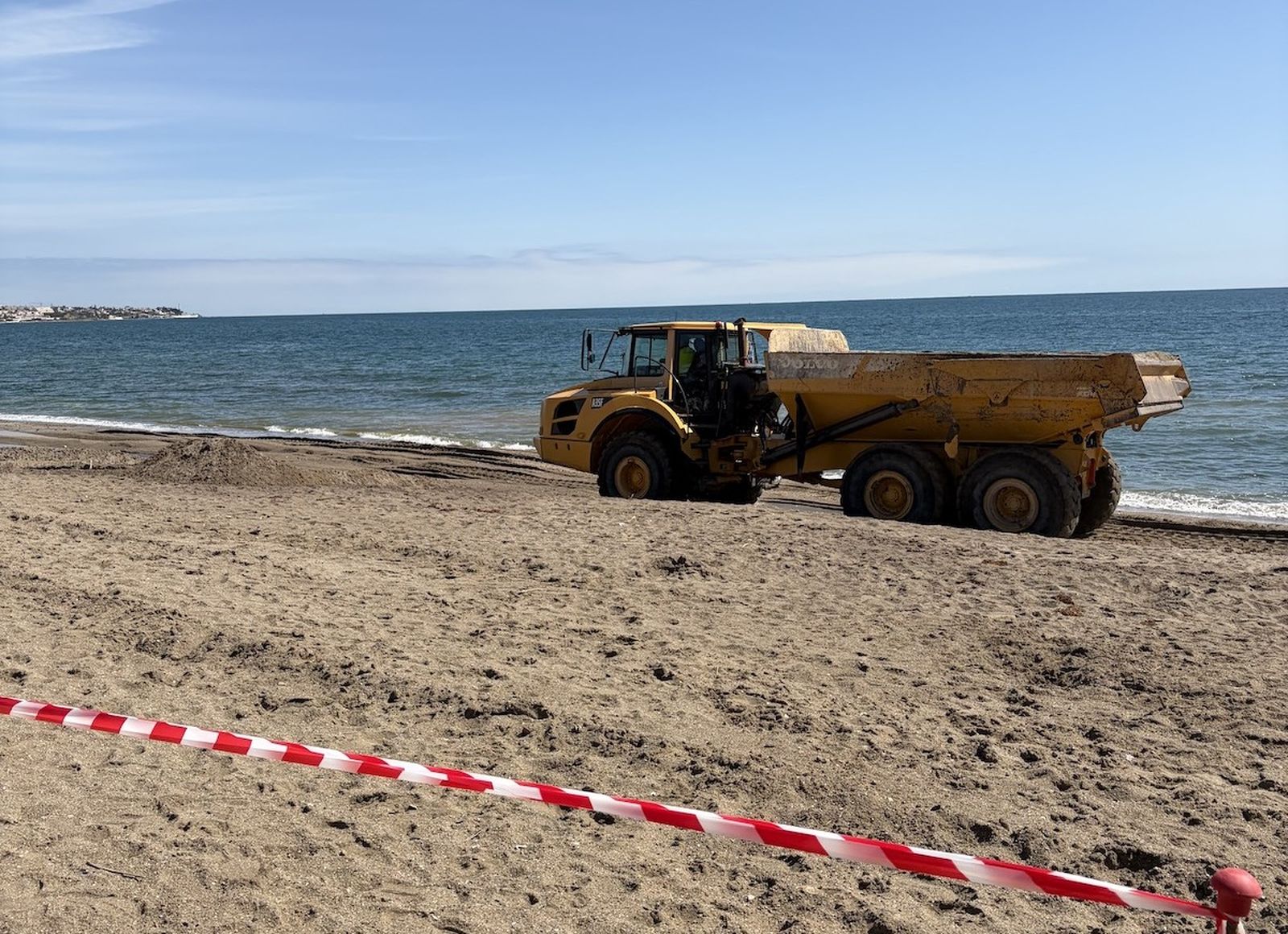 Maquinaria reponiendo arena en la playa de El Bombo.