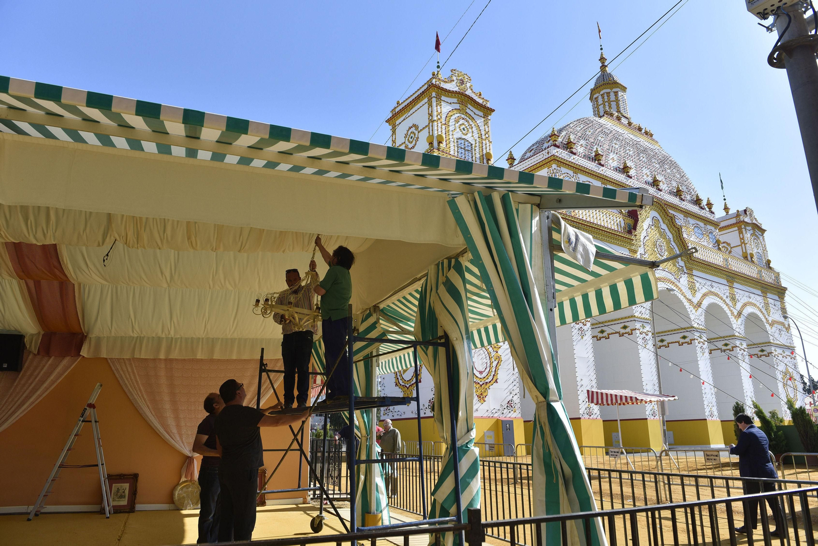 Dos hombres subidos en un andamio colocan una lampara en el interior de una caseta.