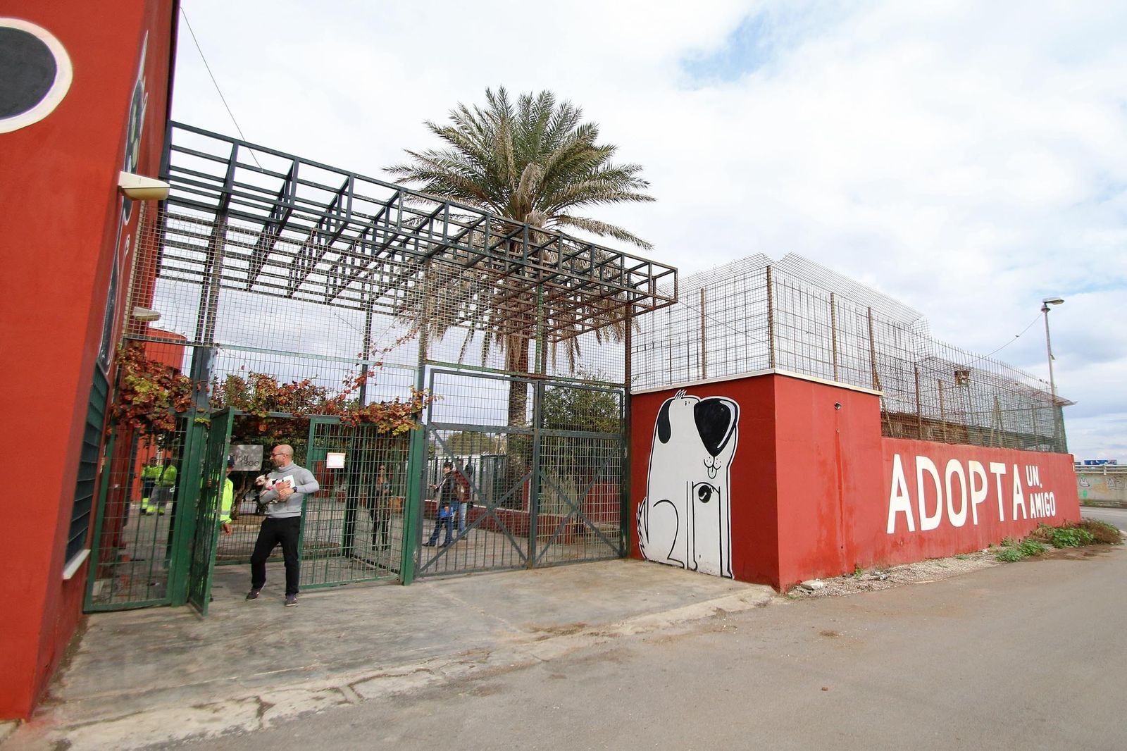 Un hombre sale del Centro Municipal con un amigo de cuatro patas en sus brazos.
