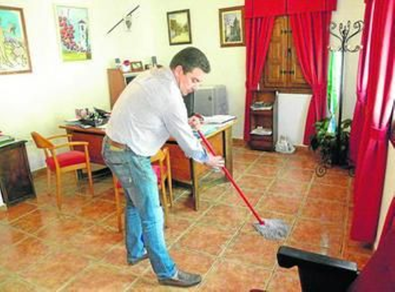 Salvador Fernández, alcalde de El Borge, fregona en mano limpiando su despacho.