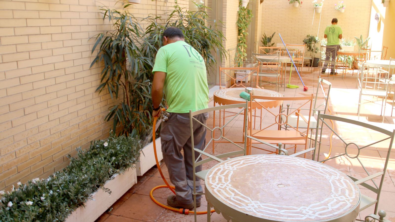 Técnicos de mantenimiento regando las jardineras del hotel.
