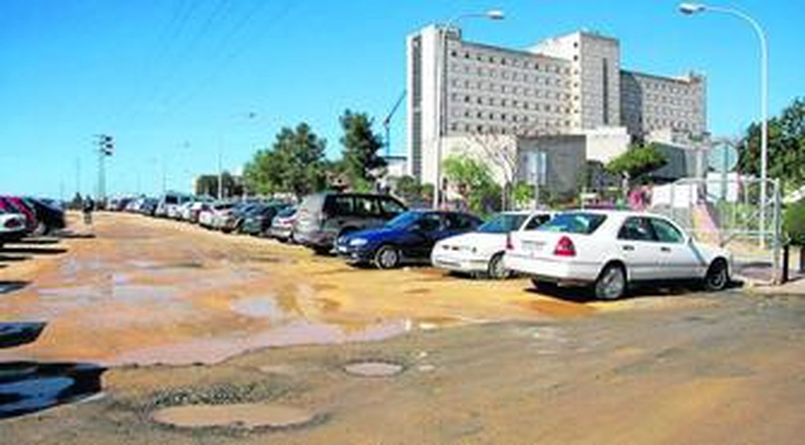 El acceso a una zona habilitada para aparcar en el Valme repleta de socavones y de fango.